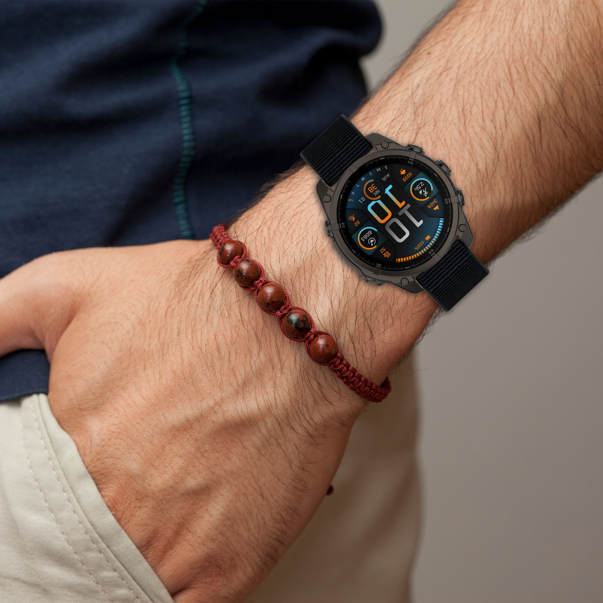 Ein Mann trägt eine Smartwatch und ein Perlenarmband am Handgelenk.
