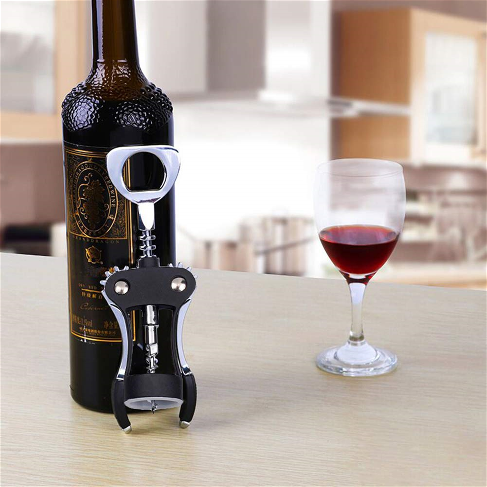Weinflasche, Korkenzieher und Glas mit Rotwein auf einem Tisch. Der Hintergrund ist unscharf.