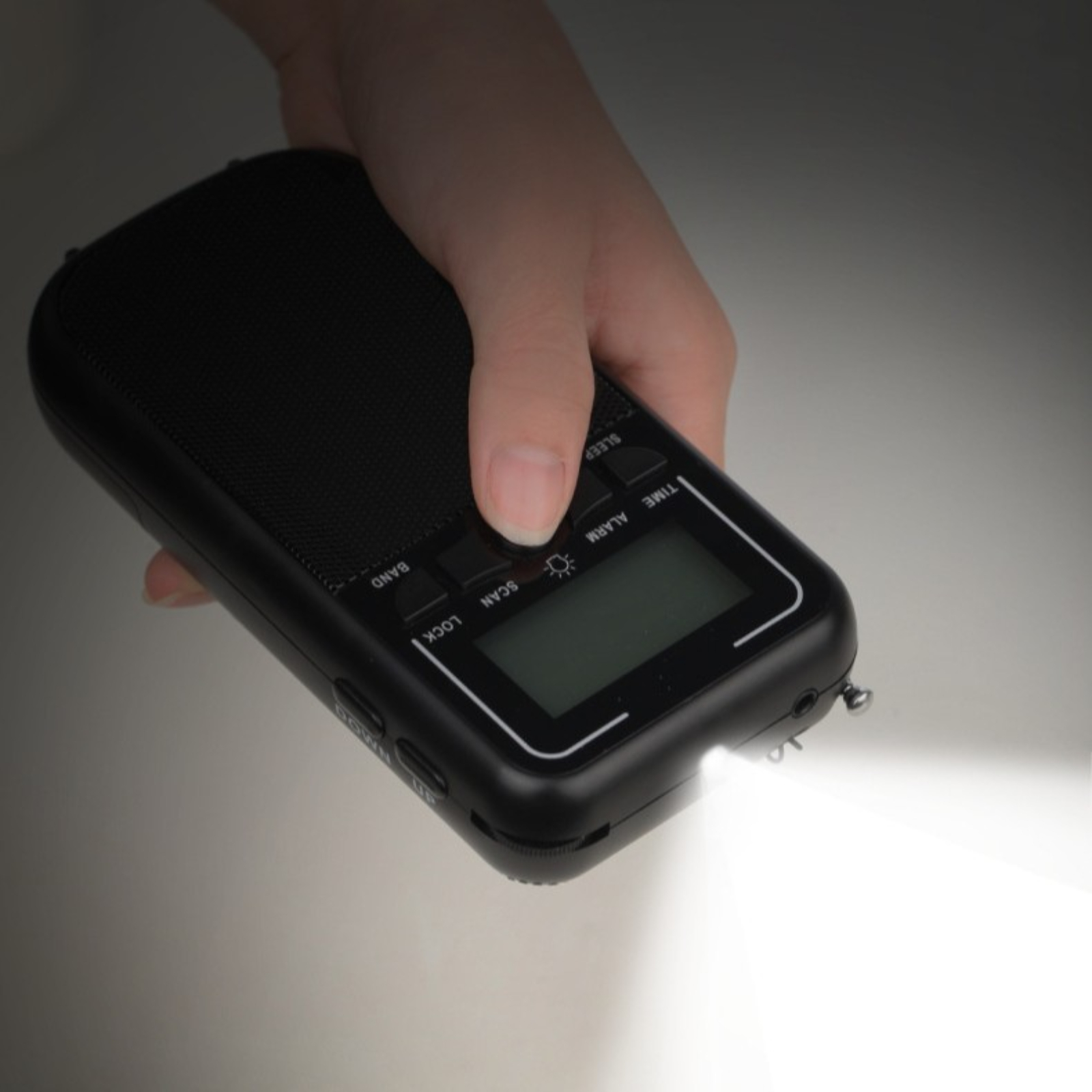 Eine Hand hält ein schwarzes tragbares Radio mit Licht und Display.