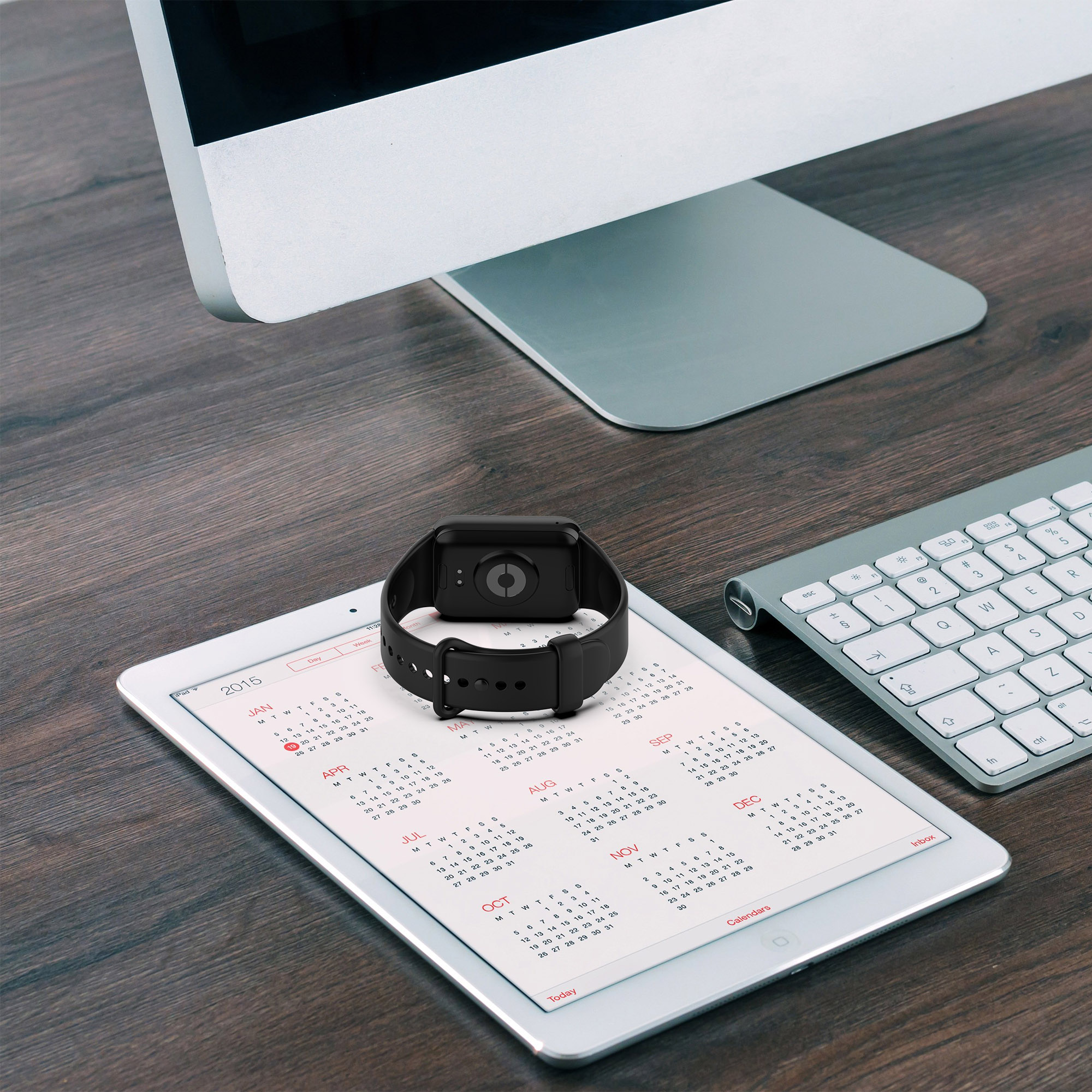 Eine Smartwatch auf einem Tablet, das einen Kalender anzeigt, mit einer Tastatur auf einem Holztisch. Die Uhr ist schwarz.