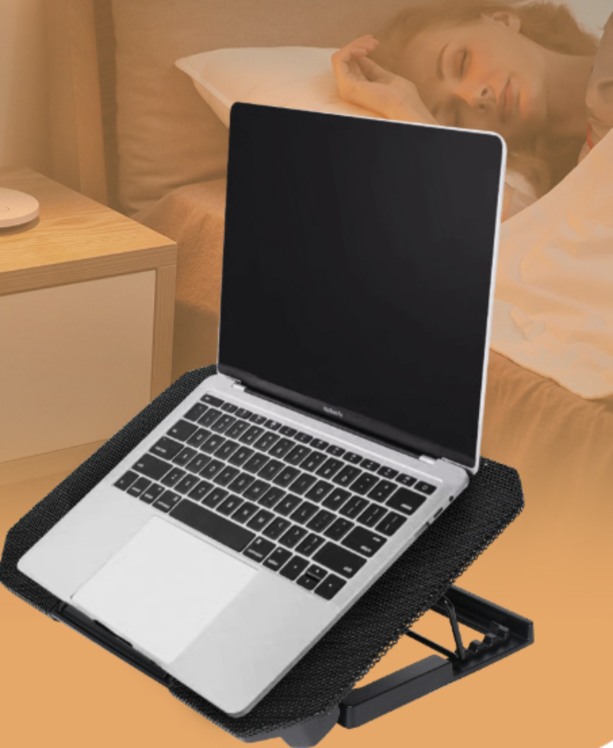 Laptop auf einem schwarzen Ständer, im Hintergrund eine schlafende Person.