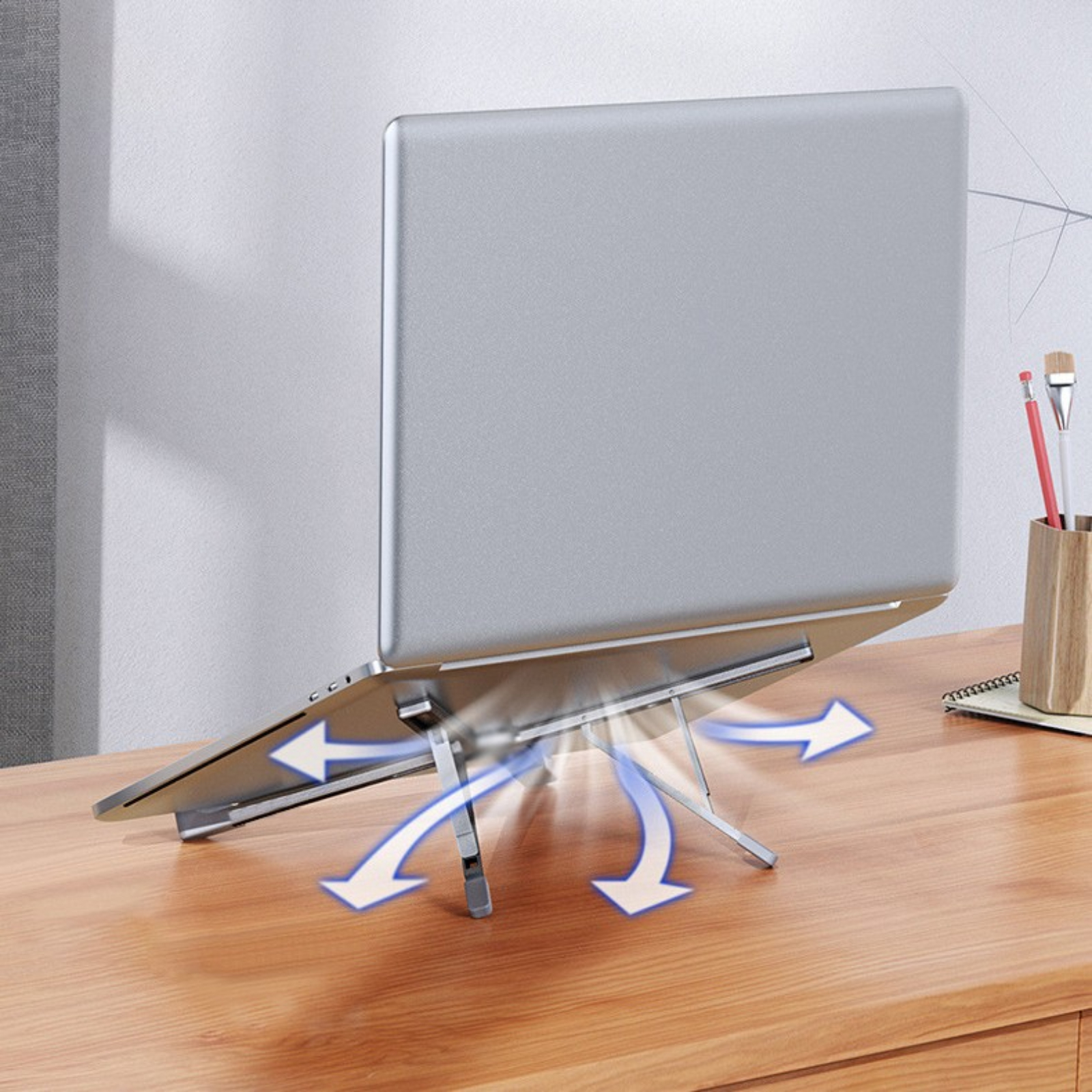 Ein Laptop auf einem silbernen Ständer mit Pfeilen, die den Luftstrom anzeigen. Der Ständer steht auf einem Holzschreibtisch.