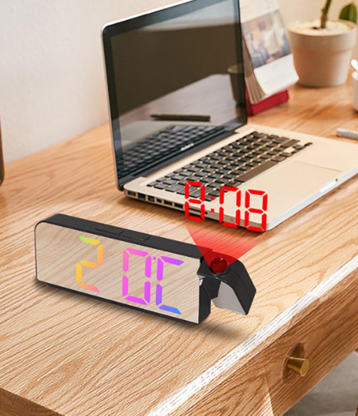 Digitaluhr zeigt die Zeit 2:06 an. Die Uhr steht auf einem Holzschreibtisch, im Hintergrund ein Laptop.
