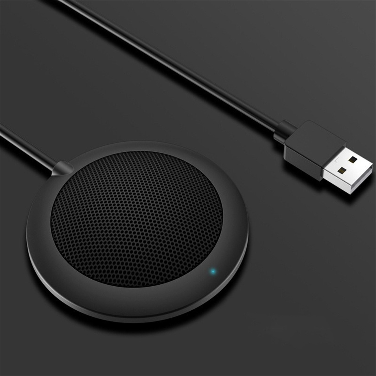 Schwarzes Mikrofon mit USB-Kabel auf dunkler Oberfläche. Ein blaues Licht leuchtet auf dem Mikrofon.
