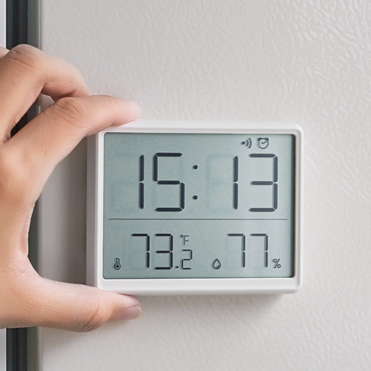 Weißes digitales Thermometer, das Zeit, Temperatur in Fahrenheit und Celsius sowie Luftfeuchtigkeit anzeigt.