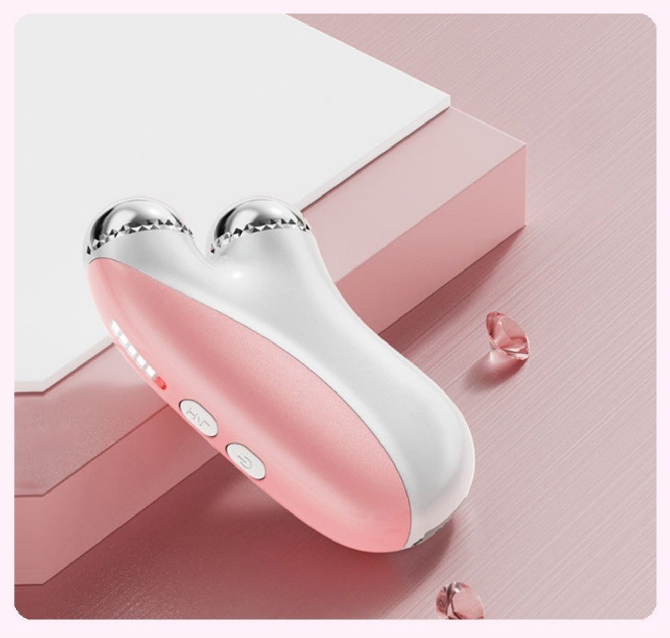 Ein rosa-weißer Gesichtsmassagegerät mit zwei Silberköpfen und Knöpfen. Rosa Hintergrund.