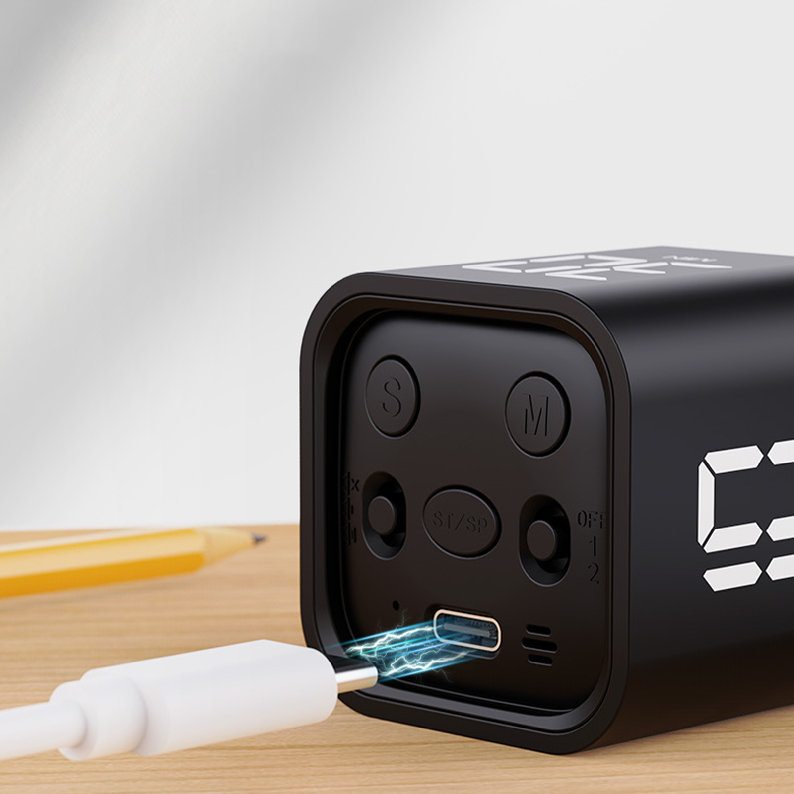 Ein schwarzer digitaler Wecker mit einem eingesteckten Ladekabel.