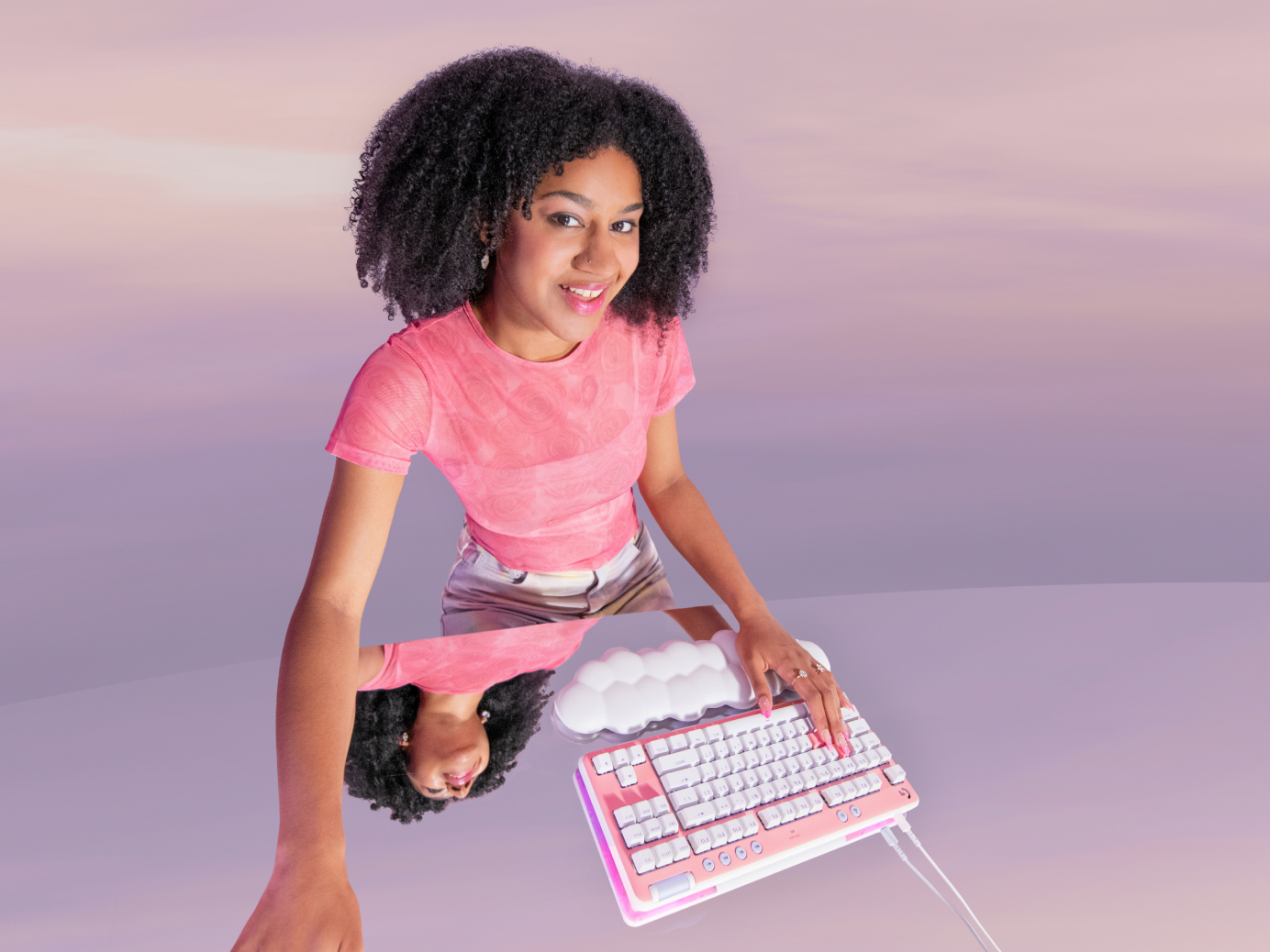Kobieta w różowej koszuli trzyma różową klawiaturę. Odbicie w lustrze.