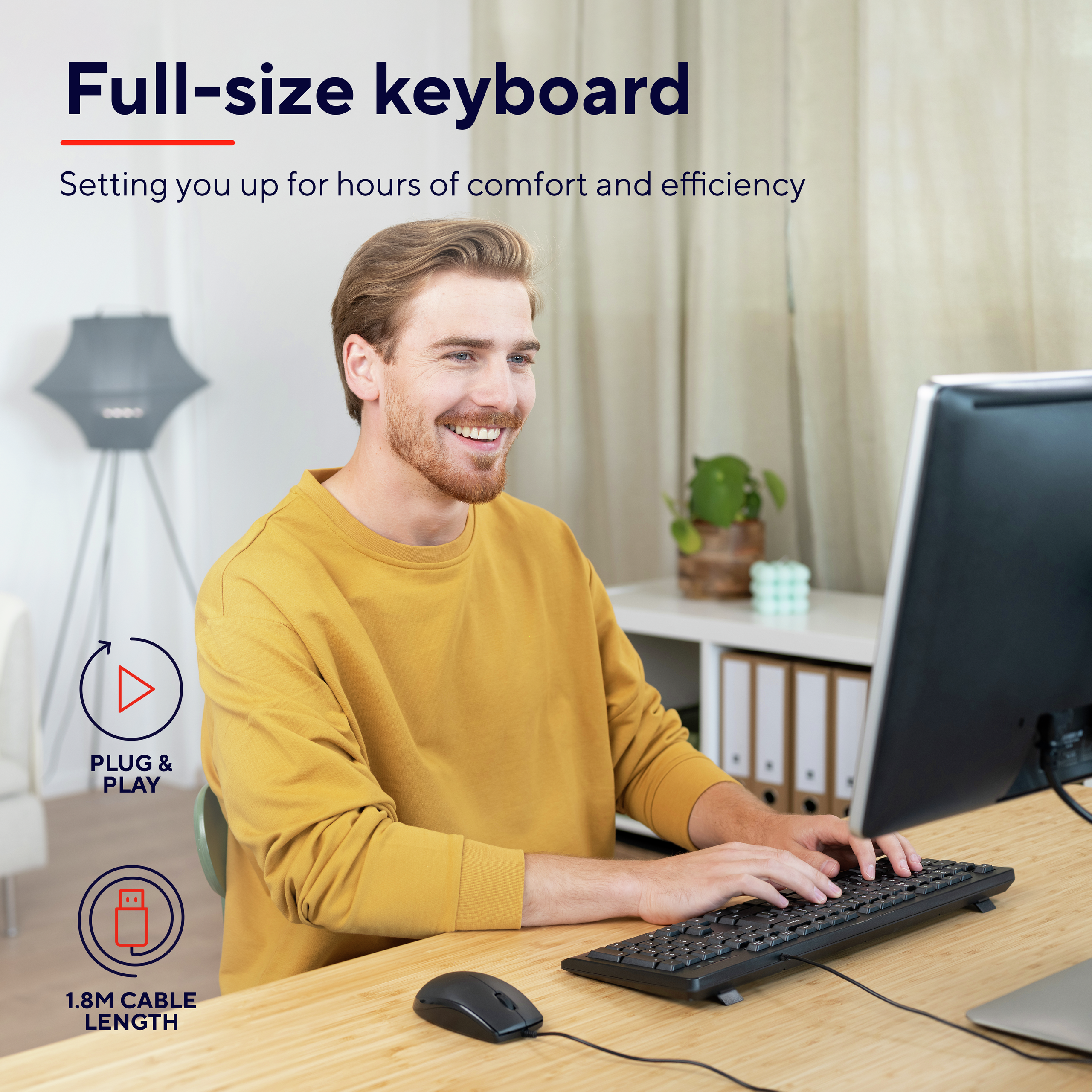 Ein Mann benutzt eine schwarze Tastatur und Maus. Er lächelt. Schreibtisch.