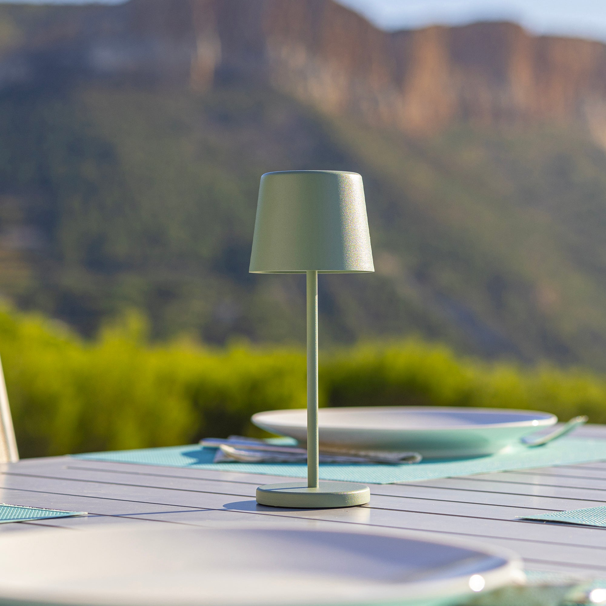 Grüne Außenlampe auf einem Tisch. Hintergrund Berge.