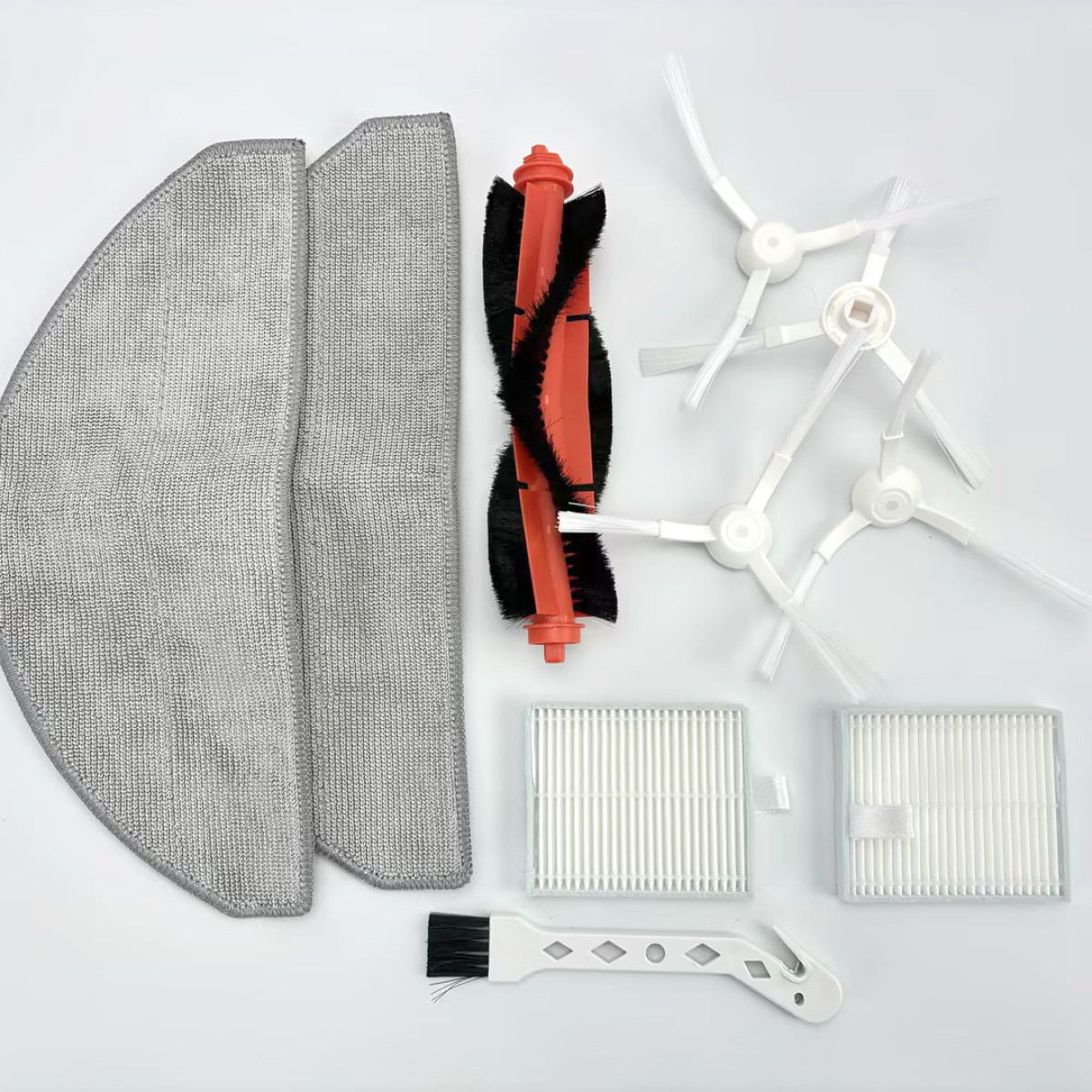 Części robota sprzątającego, w tym mopy, szczotki i filtry, rozłożone na białej powierzchni.