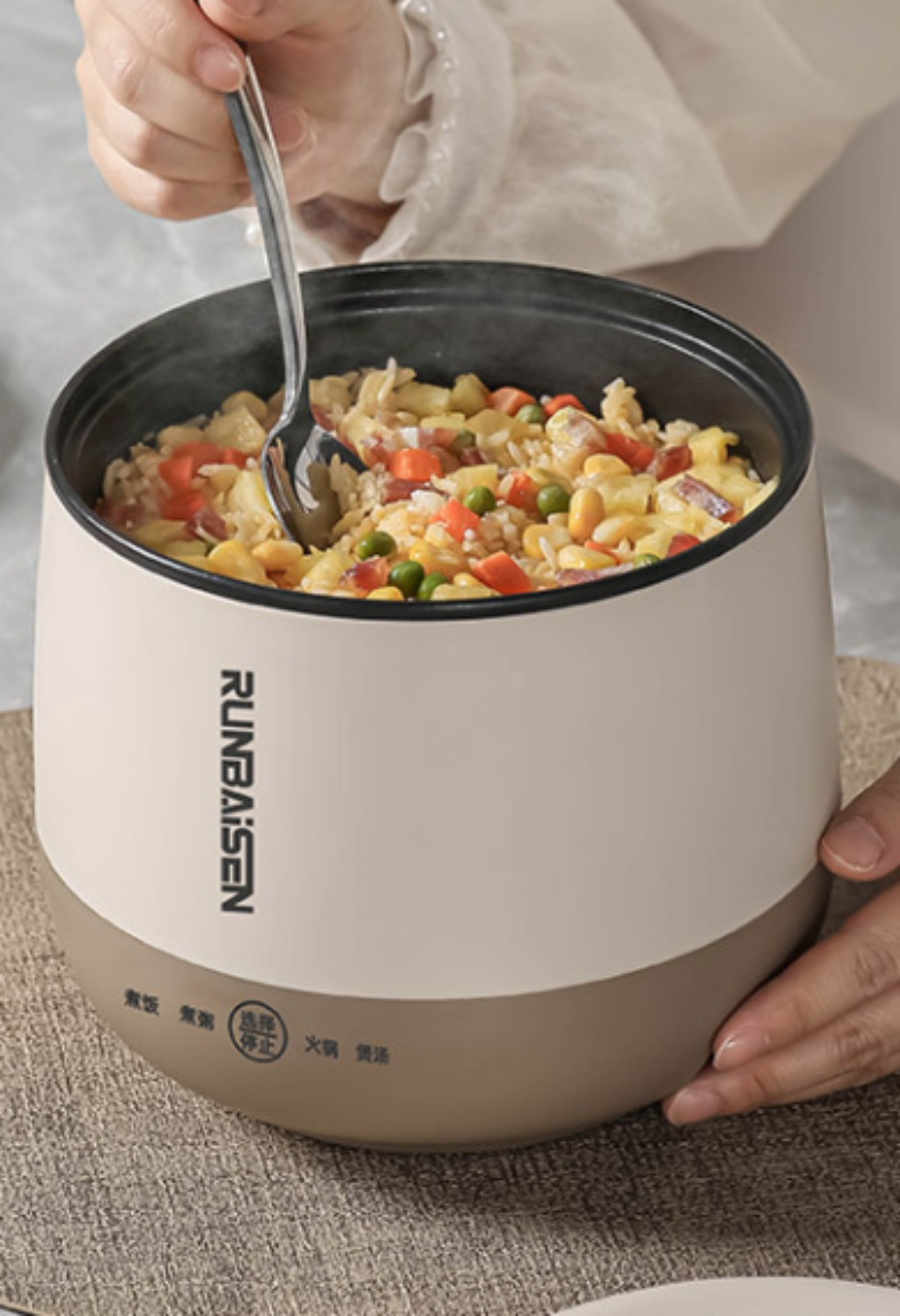 Reiskocher mit Essen darin, wird mit einem Löffel serviert. Das Äußere ist weiß und braun.