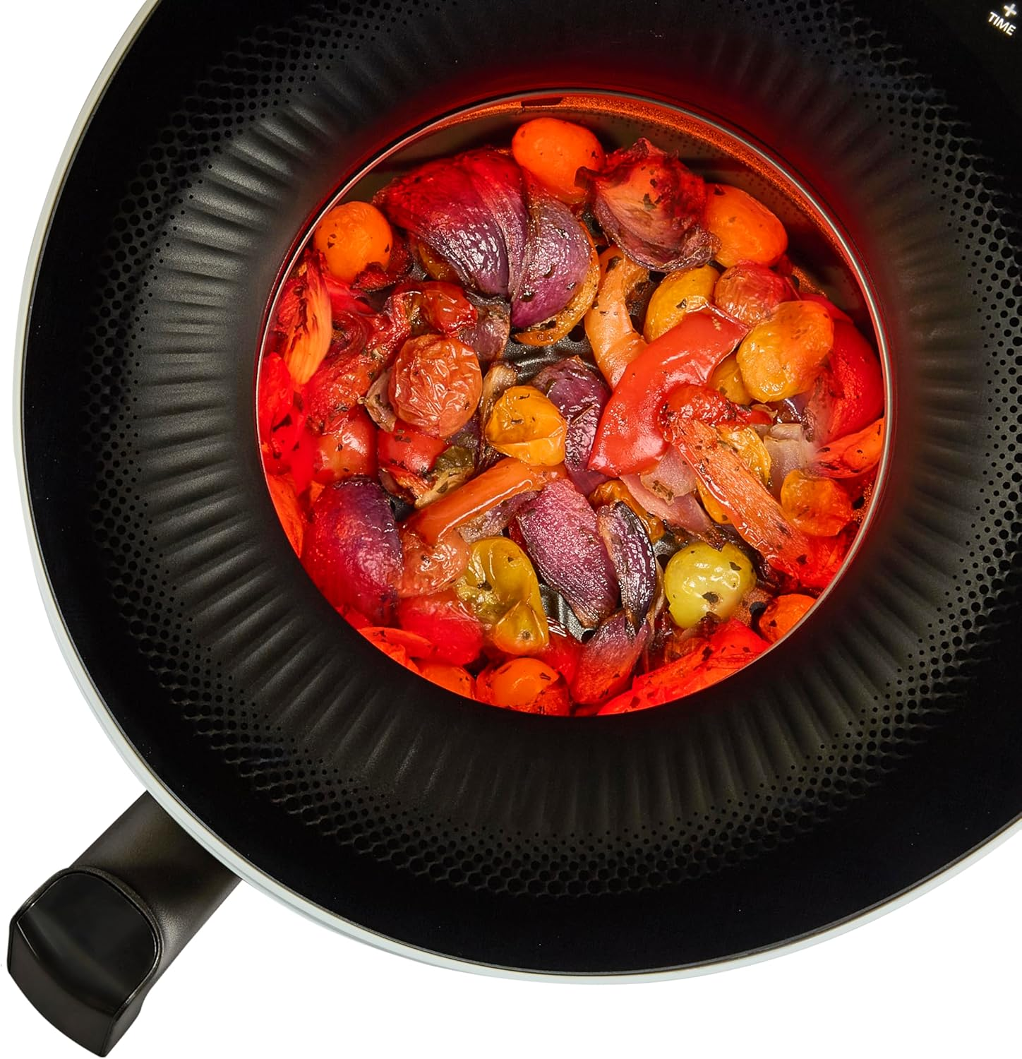 Padella con verdure all'interno. Verdure rosse e viola. Manico nero della padella.