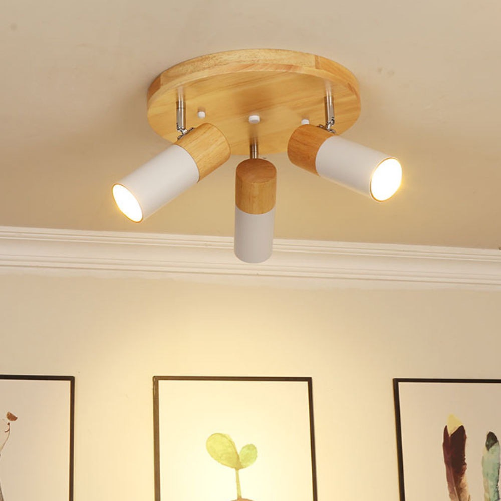 Eine Deckenlampe aus Holz mit drei verstellbaren Strahlern und zwei gerahmten Kunstwerken darunter.