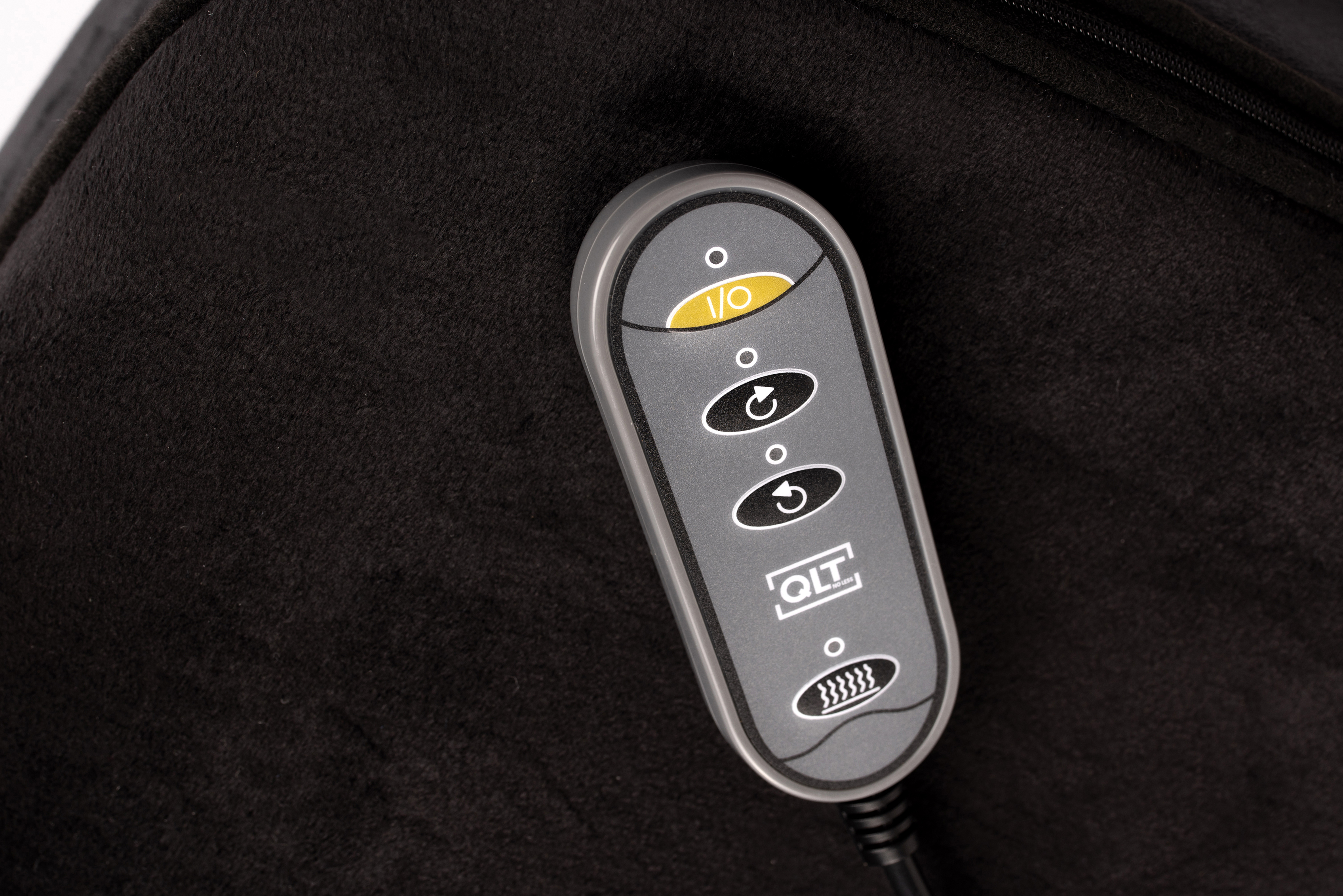 A remote control with buttons on a black cushion.