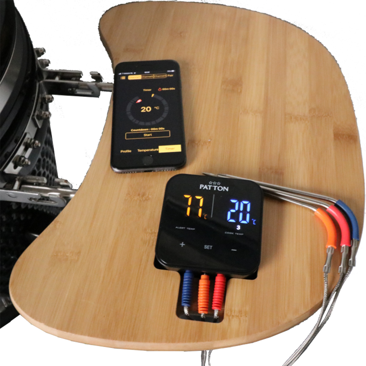 Digital meat thermometer on a wooden surface with a phone. Displays temperature readings and settings.