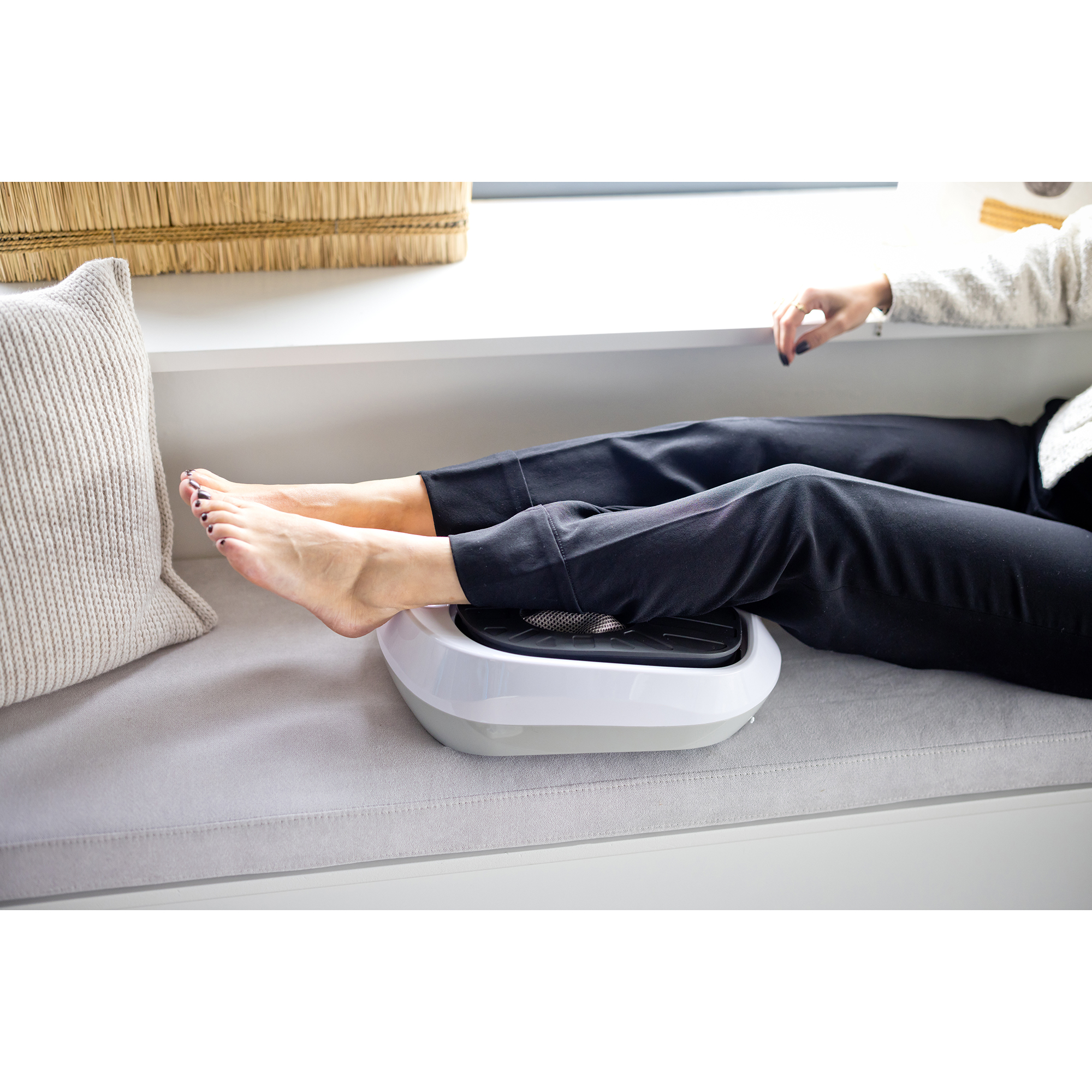 Person's feet on a foot massager. The person is resting on a grey couch.