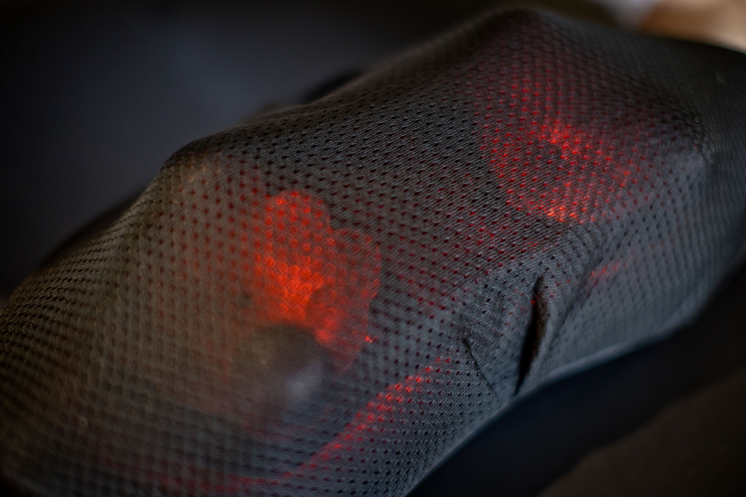 Knee covered with black mesh. Red lights shine through the mesh.