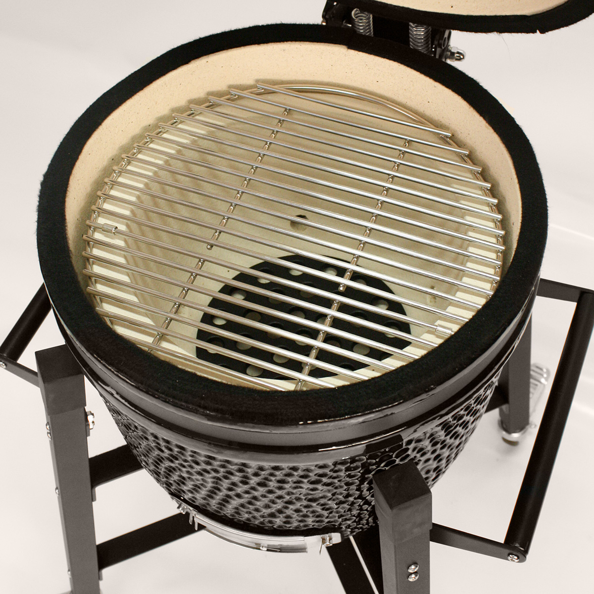Schwarzer Grill im Kamado-Stil mit offenem Deckel, Edelstahlrost und schwarzem Metallständer.
