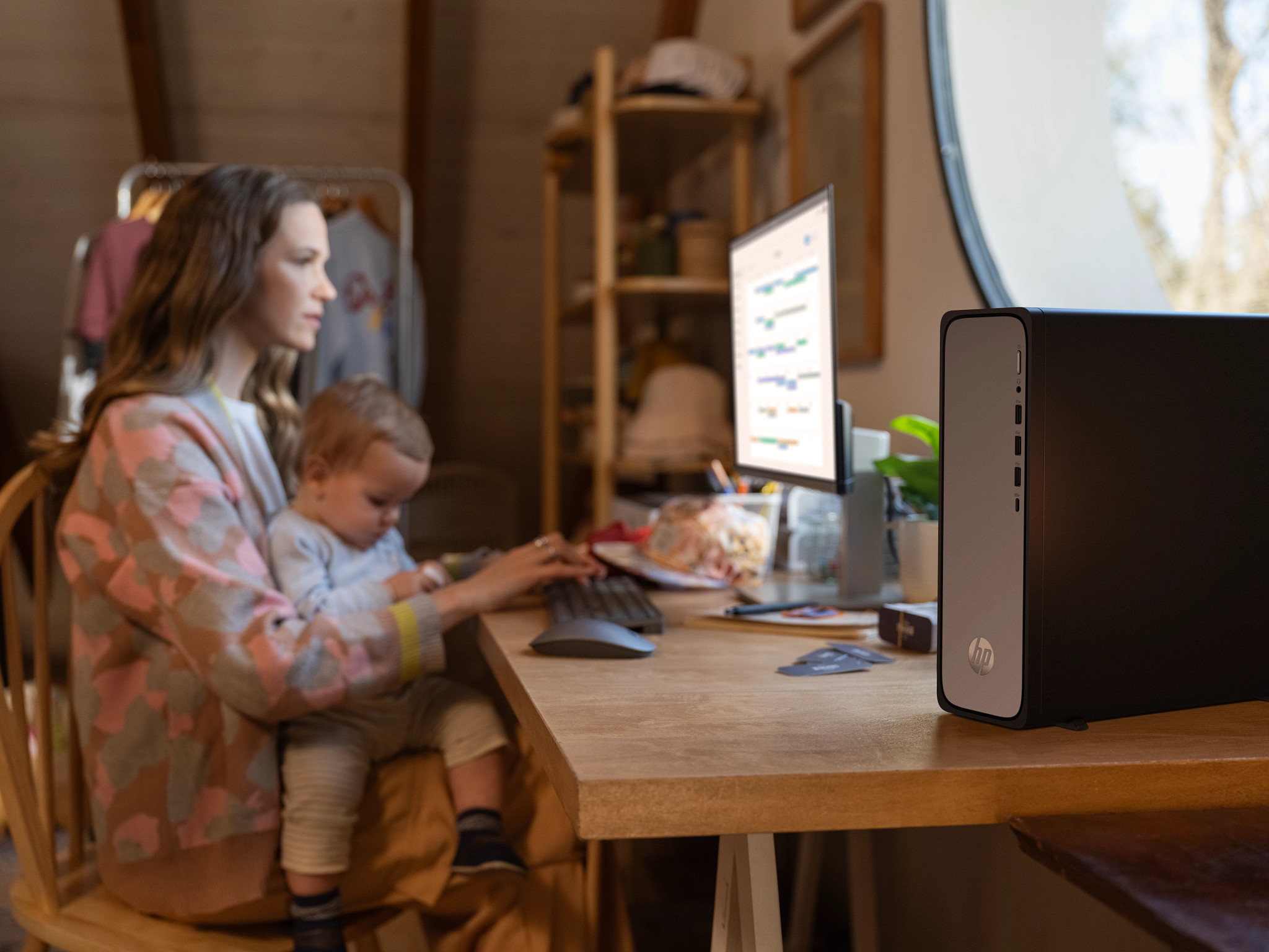 Kobieta z dzieckiem korzystająca z komputera przy biurku. Obudowa komputera po prawej.
