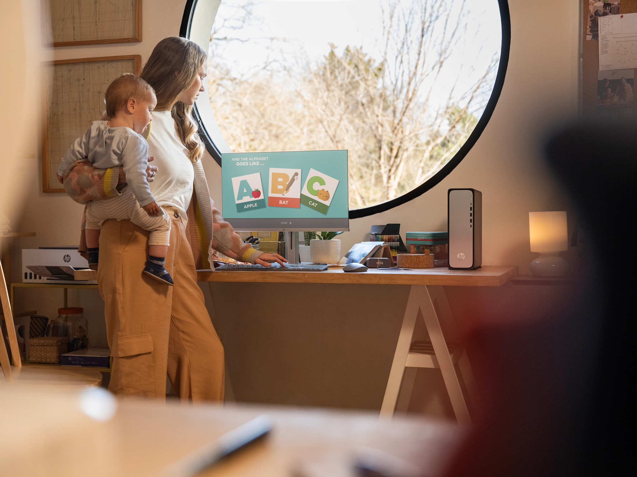 Kobieta z dzieckiem patrzy na ekran komputera. Na ekranie litery i obrazy.