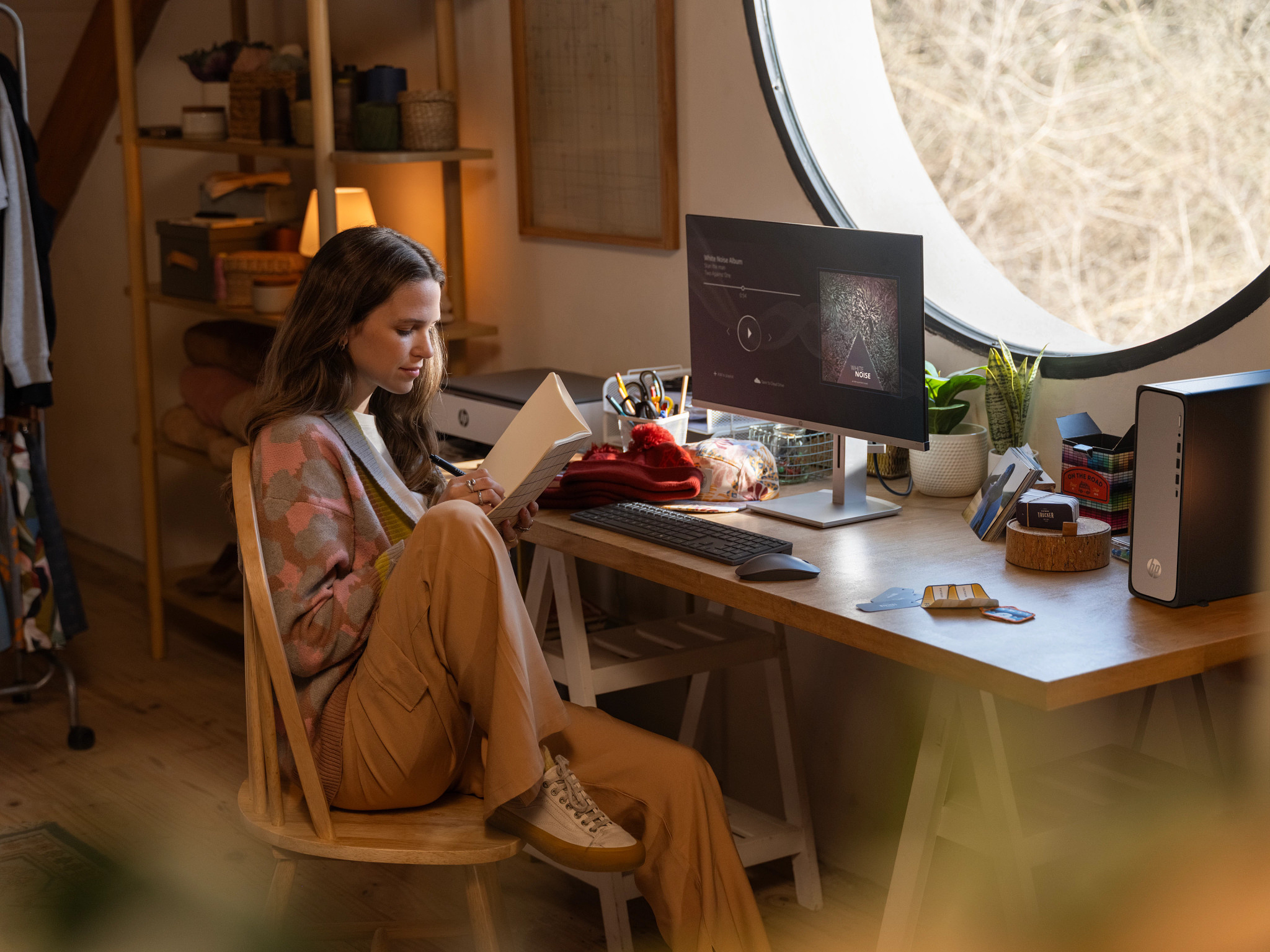 Kobieta czyta w domowym biurze. Komputer na biurku. Okno w tle.