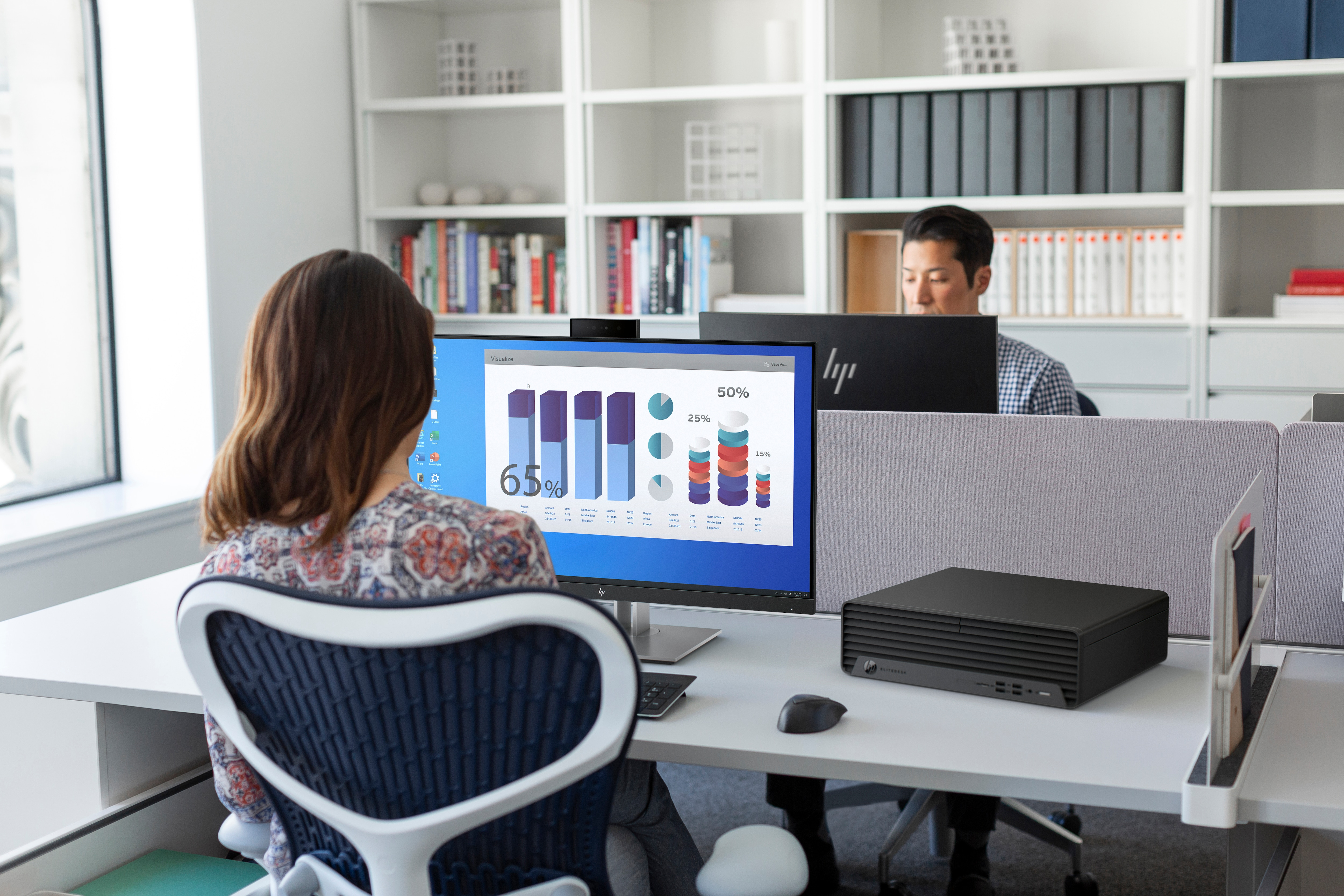 Due persone che lavorano in un ufficio, una guarda uno schermo di computer con grafici.