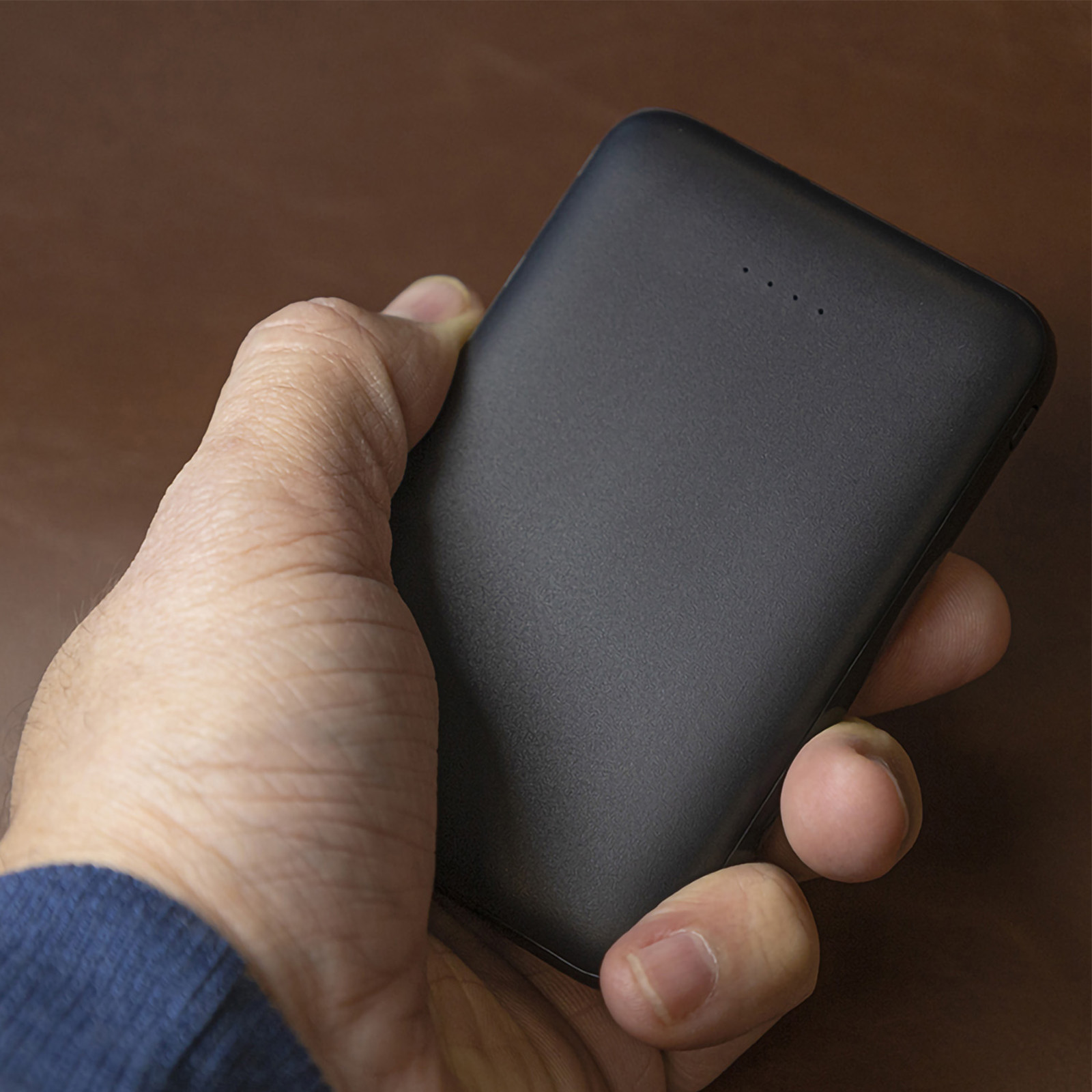 Una mano che tiene un power bank nero. La banca ha 4 punti.