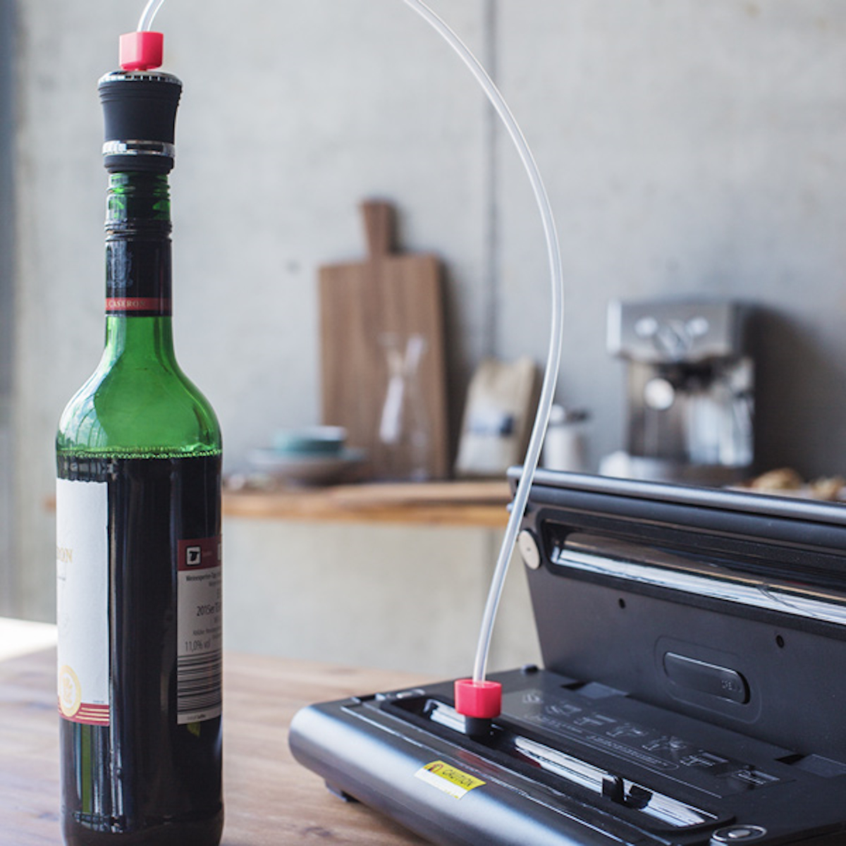 Weinflasche mit Vakuumverschluss. Vakuummaschine und Schlauch. Flasche grün, Maschine schwarz.