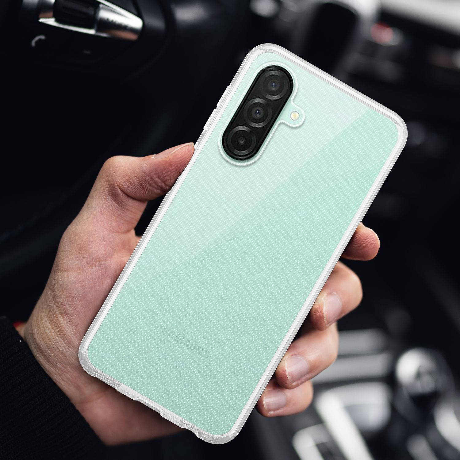 Die Hand einer Person, die ein mintgrünes Telefon mit einer durchsichtigen Hülle hält, vor verschwommenem Hintergrund.