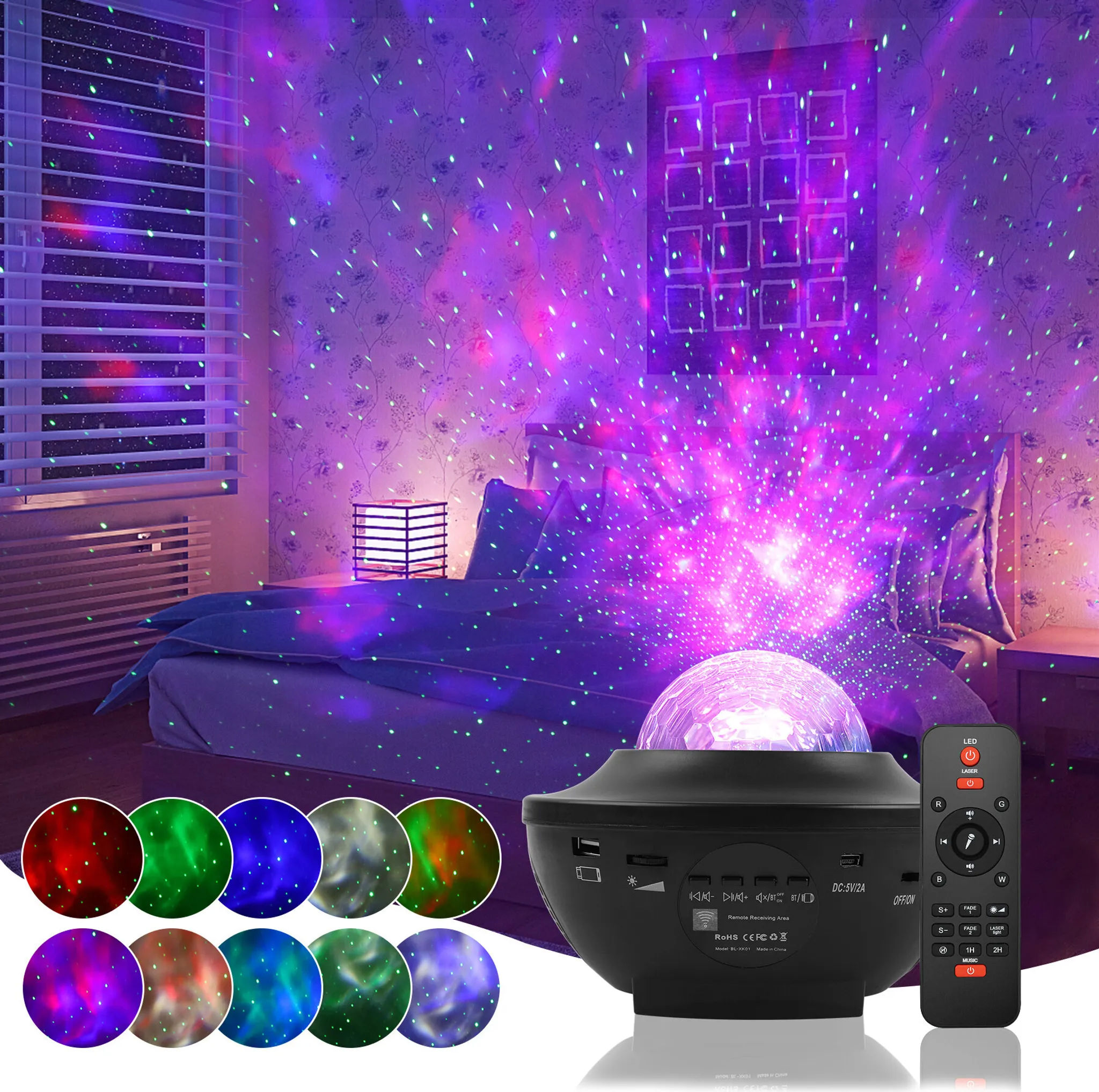 Ein schwarzer Galaxy-Projektor und Fernbedienung auf einem Bett. Die Wand zeigt Sterne. Es gibt mehrere Farben.
