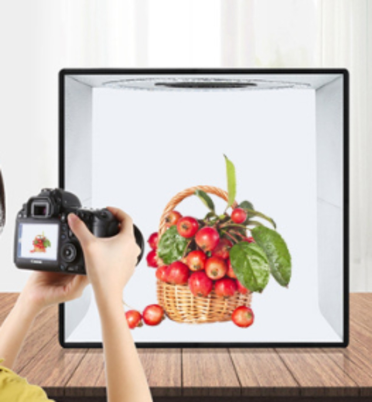 Eine Person fotografiert einen Korb voller roter Äpfel. Aufbau in einer weißen Fotobox.