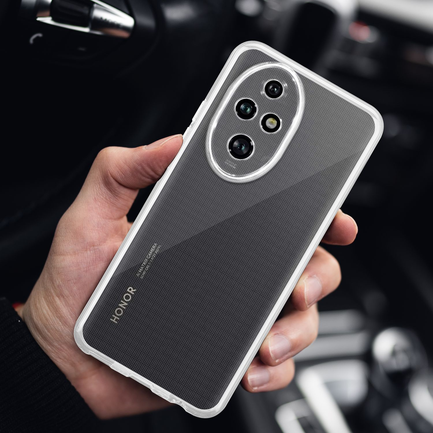 Hand hält ein Telefon in einer transparenten Hülle. Das Telefon hat mehrere Kameras. Der Hintergrund ist ein Autointerieur.