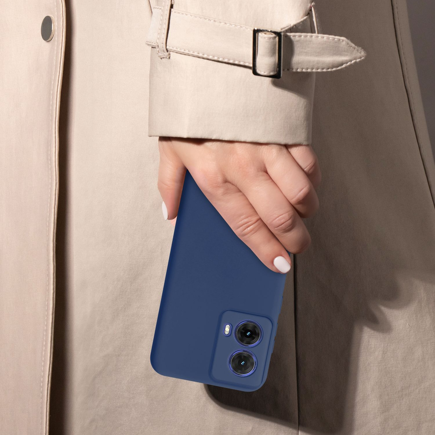 Hand hält marineblaues Telefon, beiger Trenchcoat im Hintergrund.