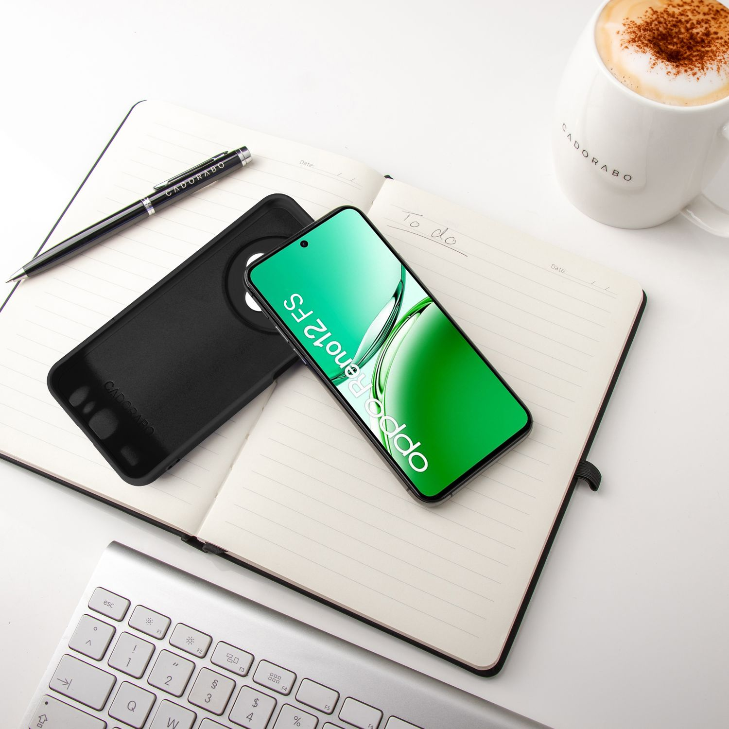 Notizbuch mit Telefon, Stift und Kaffeetasse. Telefon hat grünen Bildschirm mit Oppo.