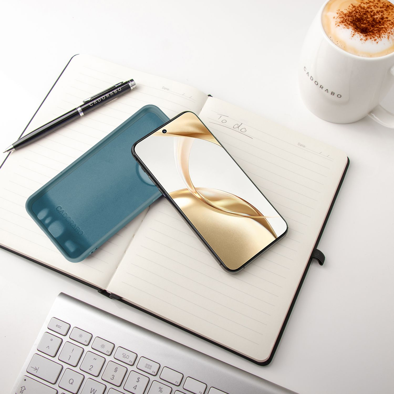 Telefon und Hülle auf einem Notizbuch. Tasse und Stift liegen daneben. Weißer Hintergrund.