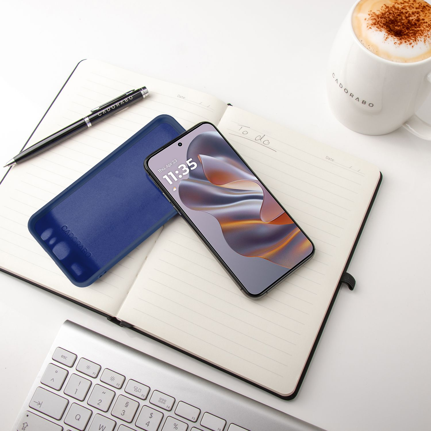 Desktop-Setup mit Telefon, Stift, Notizbuch und einer Kaffeetasse. Das Telefon befindet sich auf dem Notizbuch.
