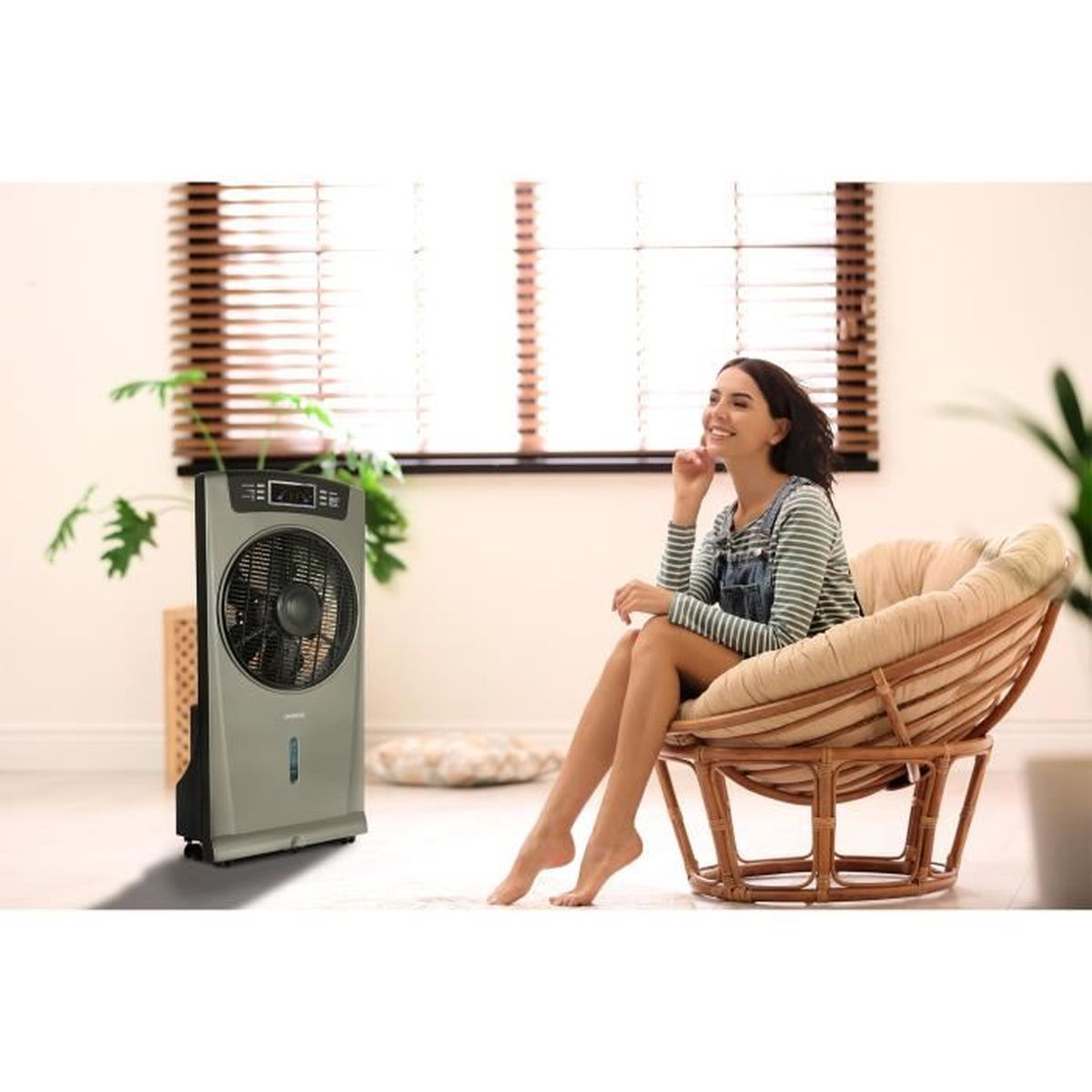 Frau lächelt und sitzt in der Nähe eines grauen Ventilators und eines Papasan-Stuhls.