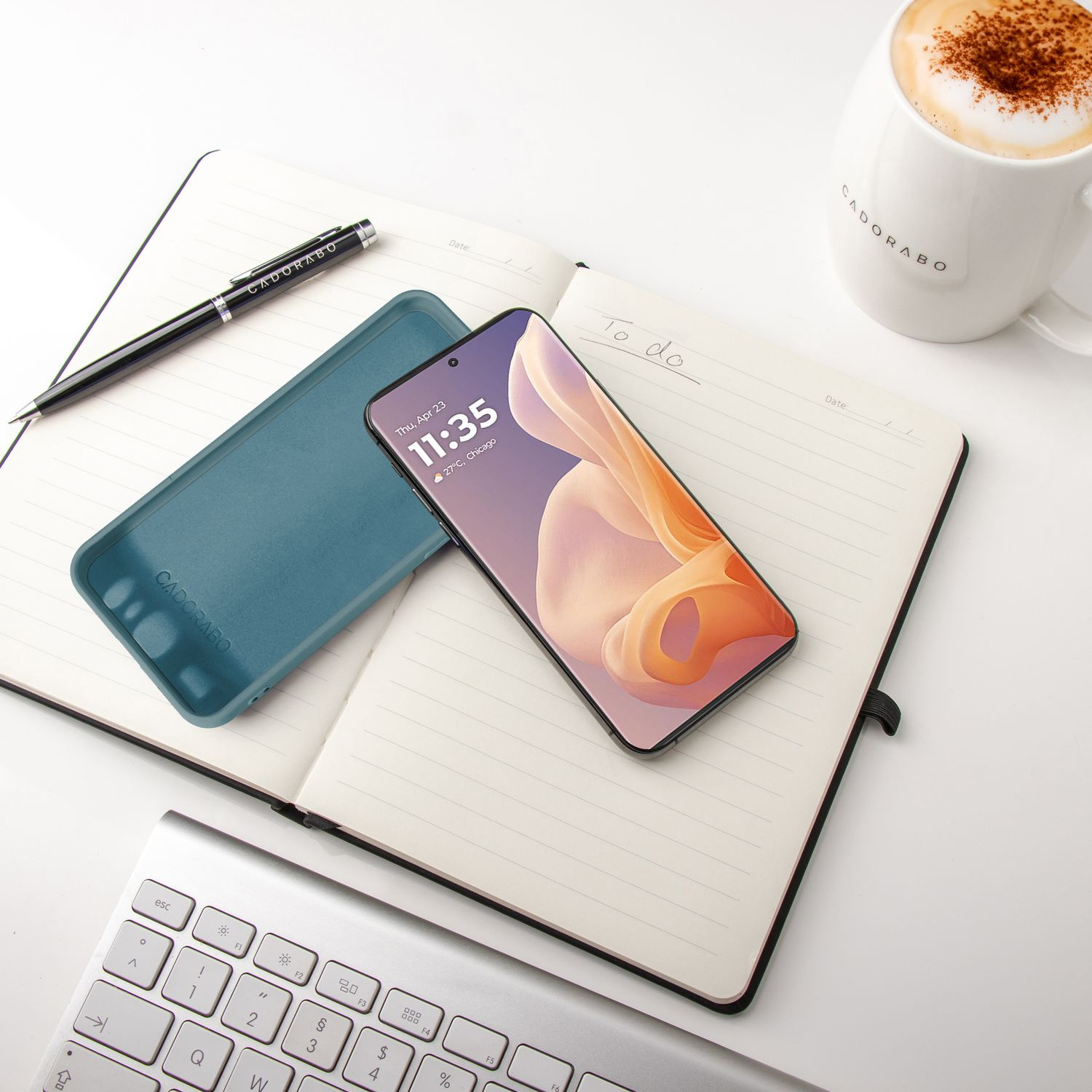 Telefon und Hülle auf Notizbuch mit Stift und Kaffeebecher. Weißer Hintergrund.