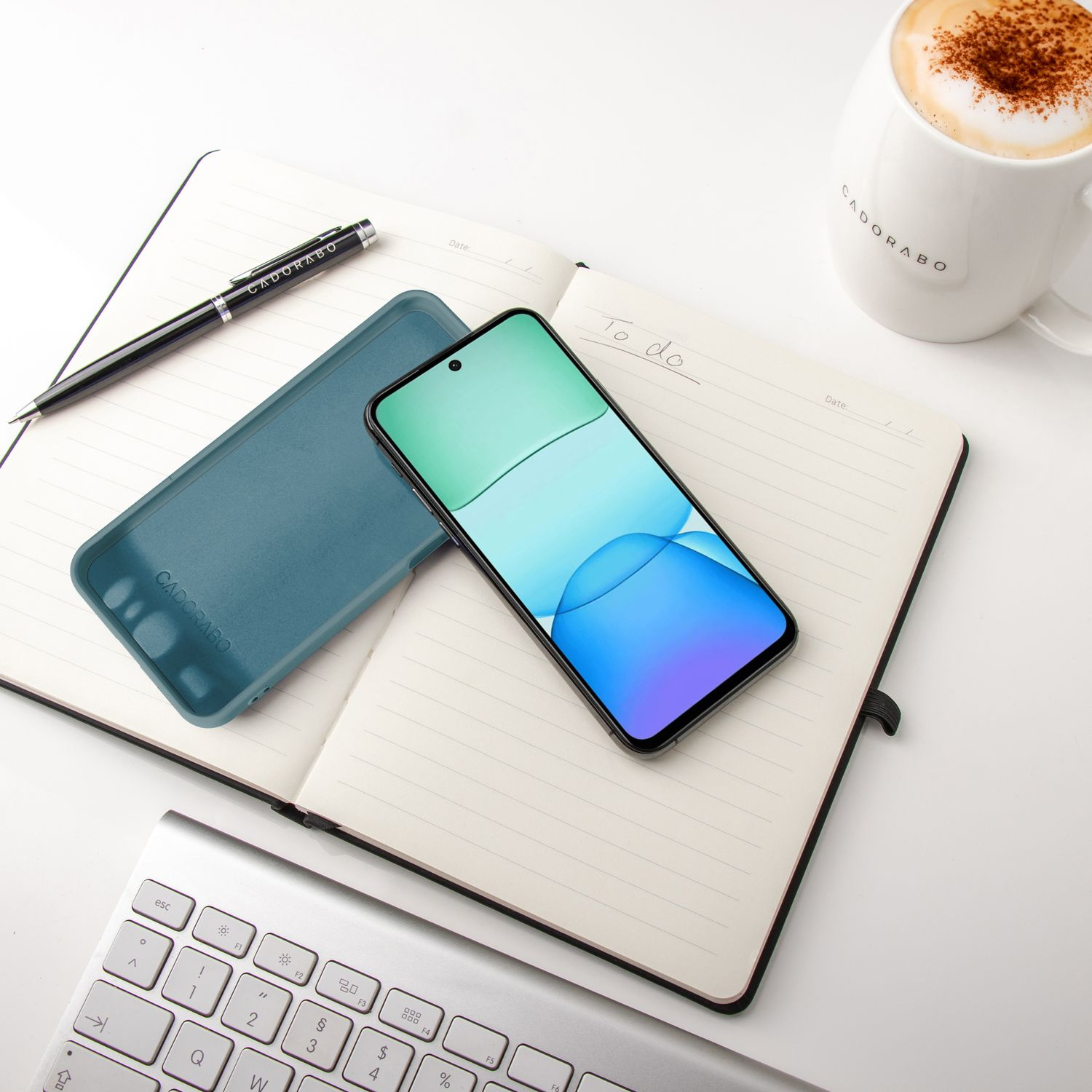 Telefon, Hülle, Notizbuch, Stift und Kaffeetasse auf weißer Oberfläche. Weißer Hintergrund.
