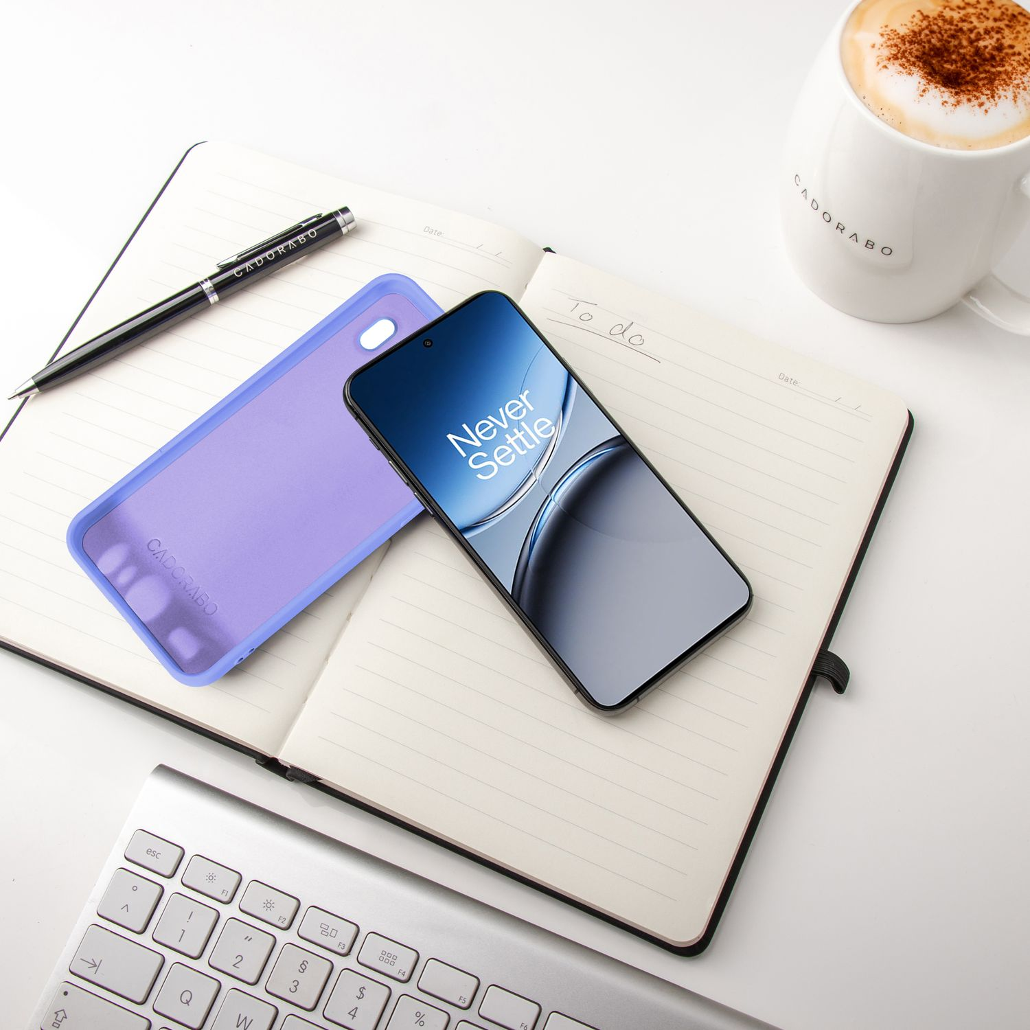 Ein Notizbuch mit einem Telefon darauf, ein Stift, eine Handyhülle und eine Tasse Kaffee.