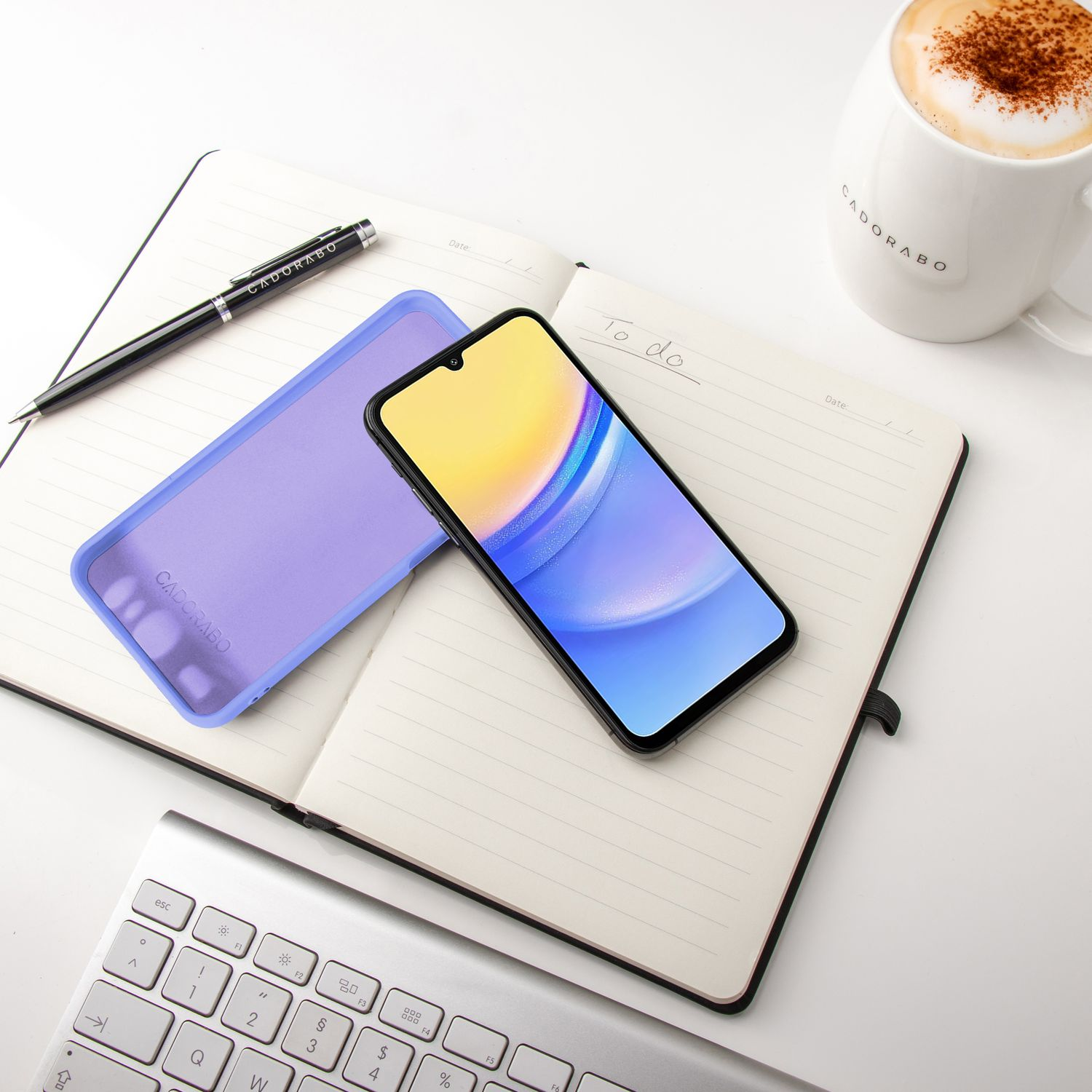 Telefon, Hülle, Stift und Kaffeetasse auf Notizbuch. Tastatur im Hintergrund. Text 'To do'.