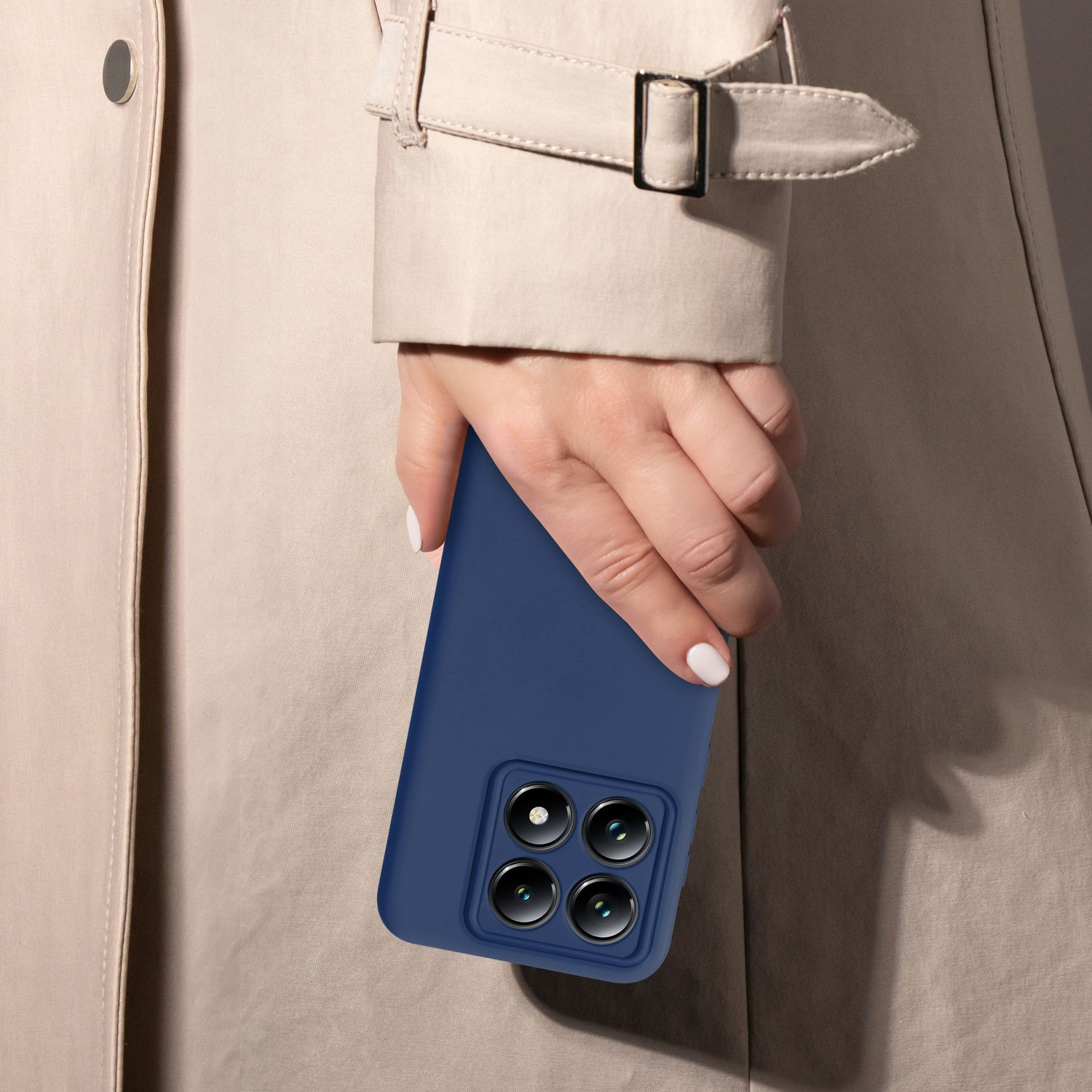 Eine Hand hält eine blaue Handyhülle mit Kameradetail vor einem beigen Trenchcoat.