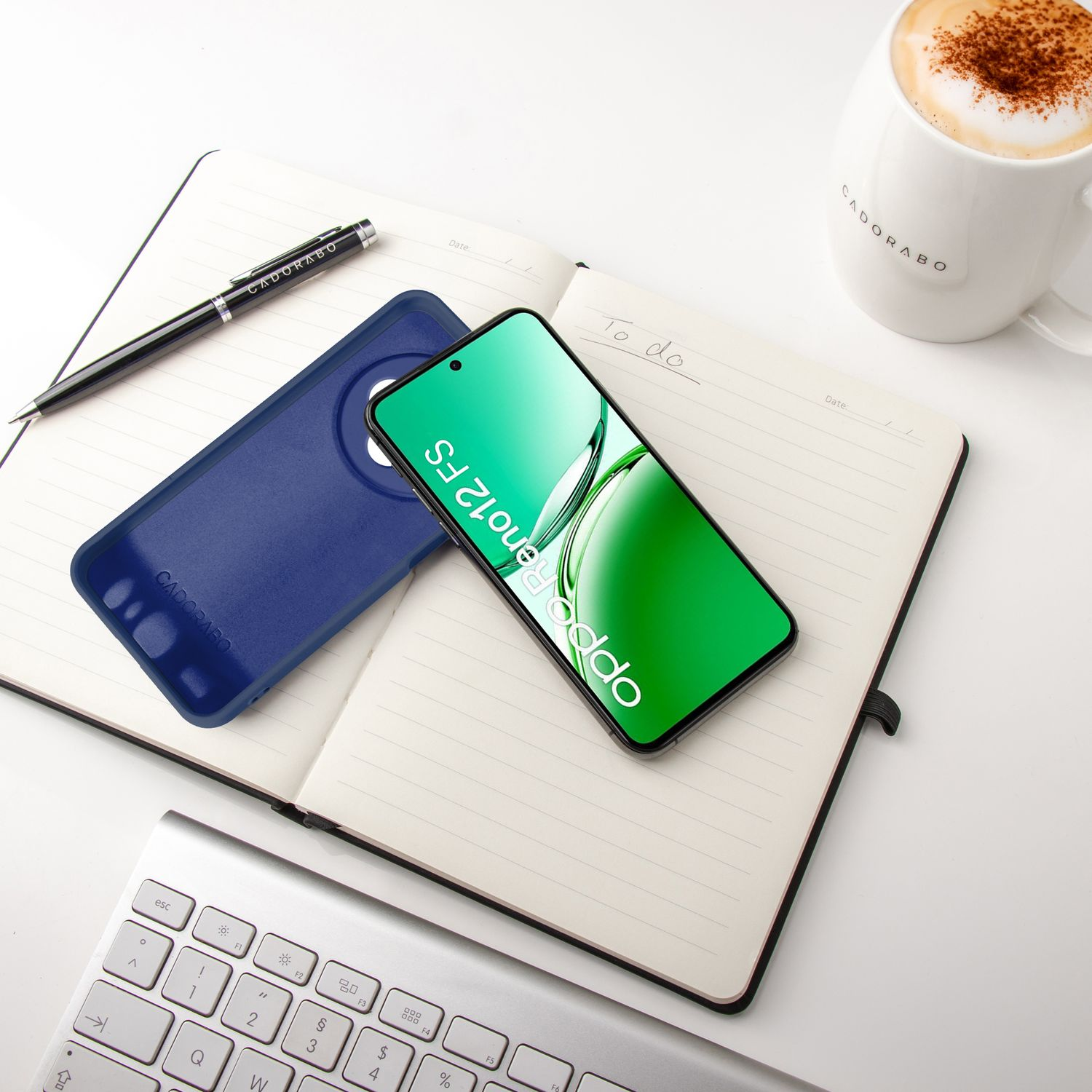 Offenes Notizbuch mit Telefon, Hülle, Stift und Becher. Tastatur unten. Weißer Hintergrund.