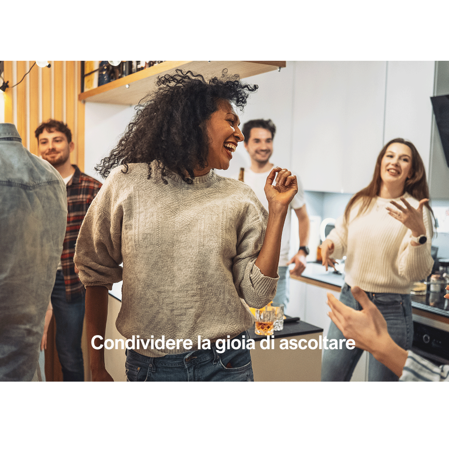 Gruppo di persone che ballano e sorridono in una cucina ben illuminata.