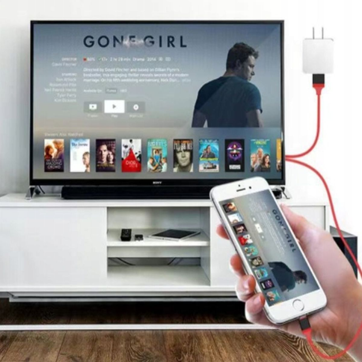 Telefon wyświetlający filmy jest podłączony do telewizora za pomocą czerwonego kabla.