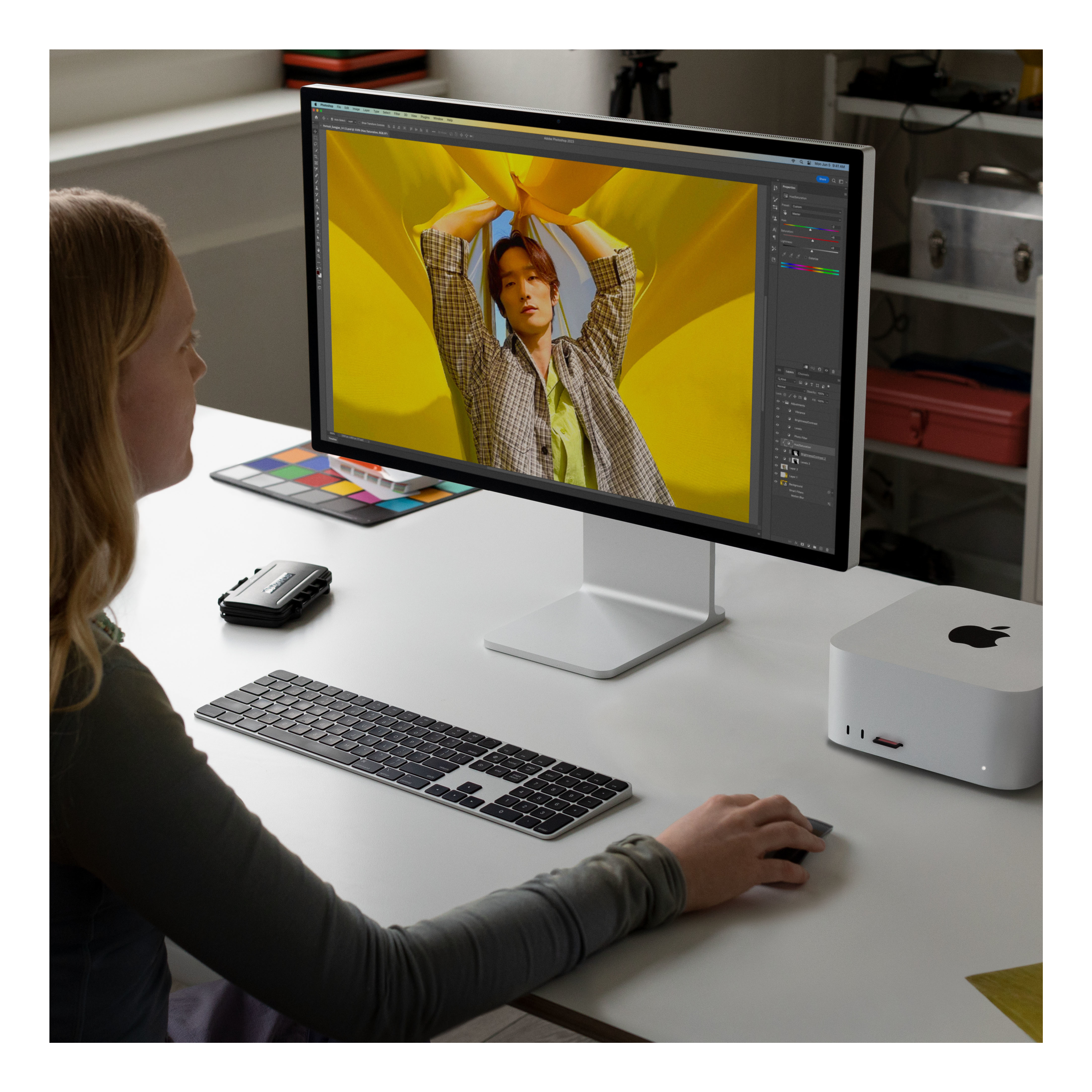 Donna che usa tastiera e mouse con un monitor che mostra un'interfaccia di editing di immagini.