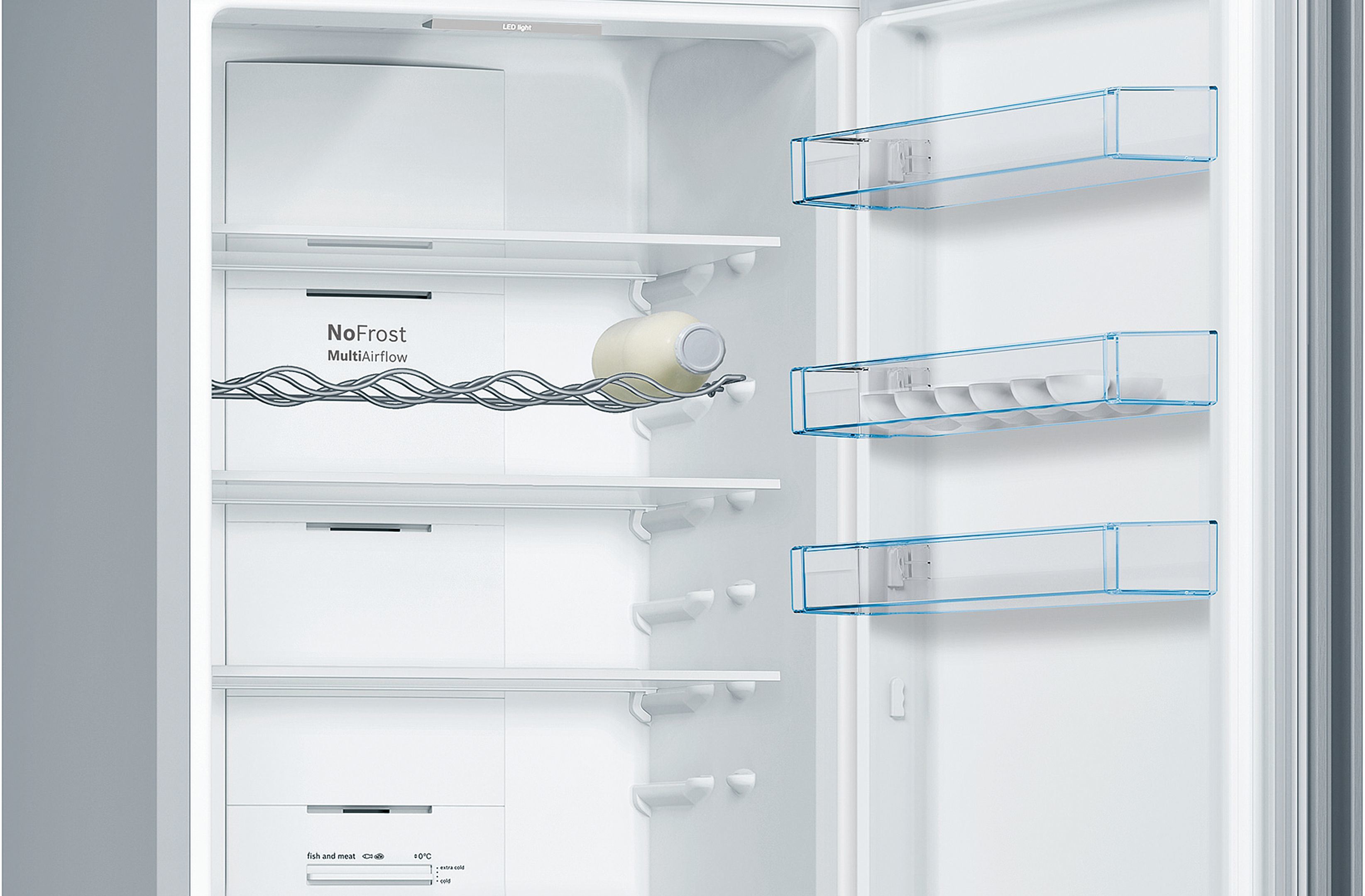 Interior de refrigerador, abierto. Estantes blancos, cajones y una botella de leche son visibles.