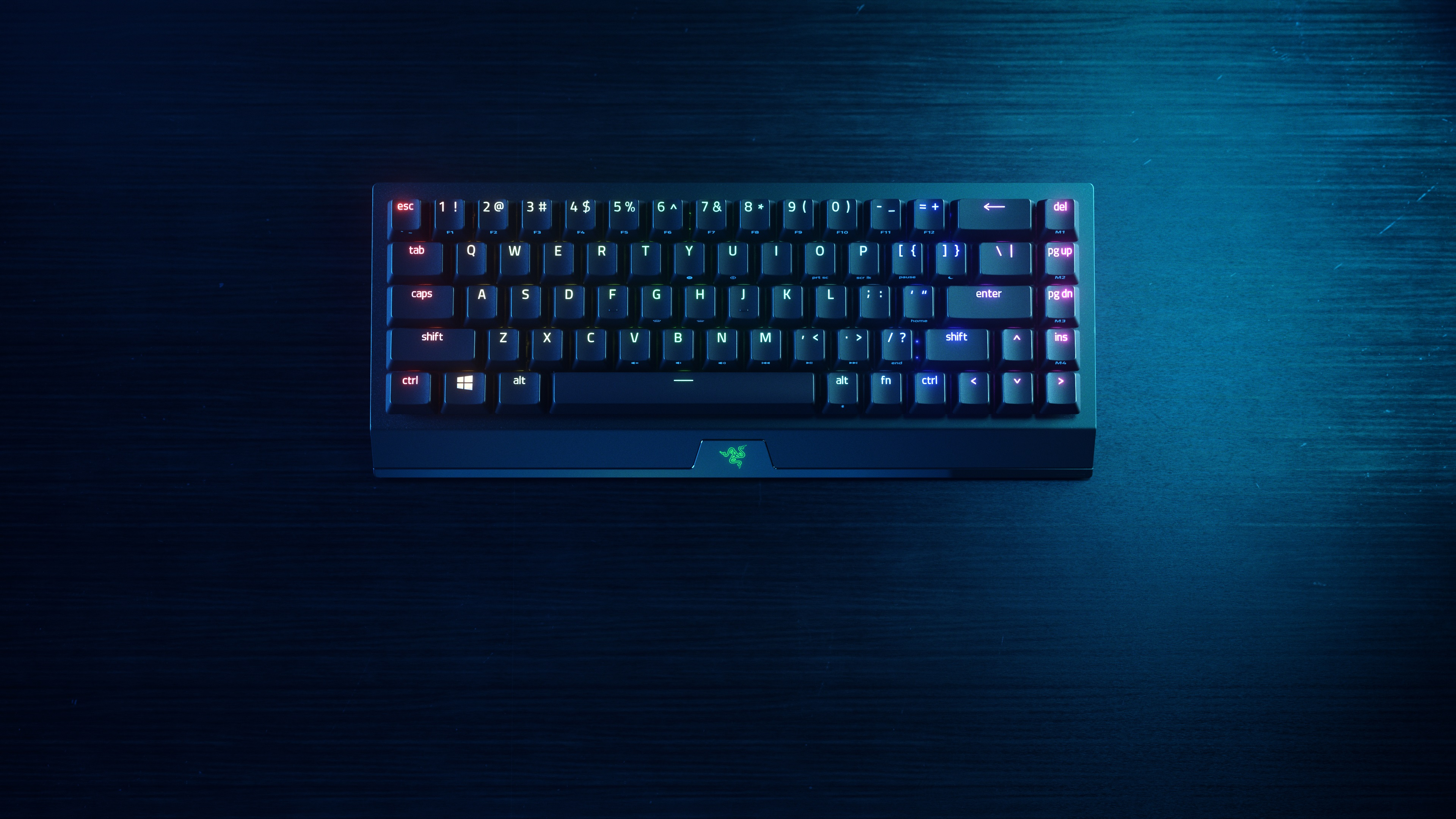 Een zwart toetsenbord met RGB-achtergrondverlichting op een houten tafel.