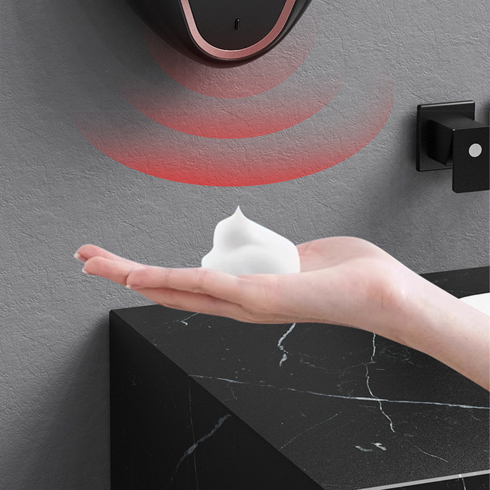 Eine Hand mit Schaumseife, die Schaum von einem Sensor-Seifenspender erhält.
